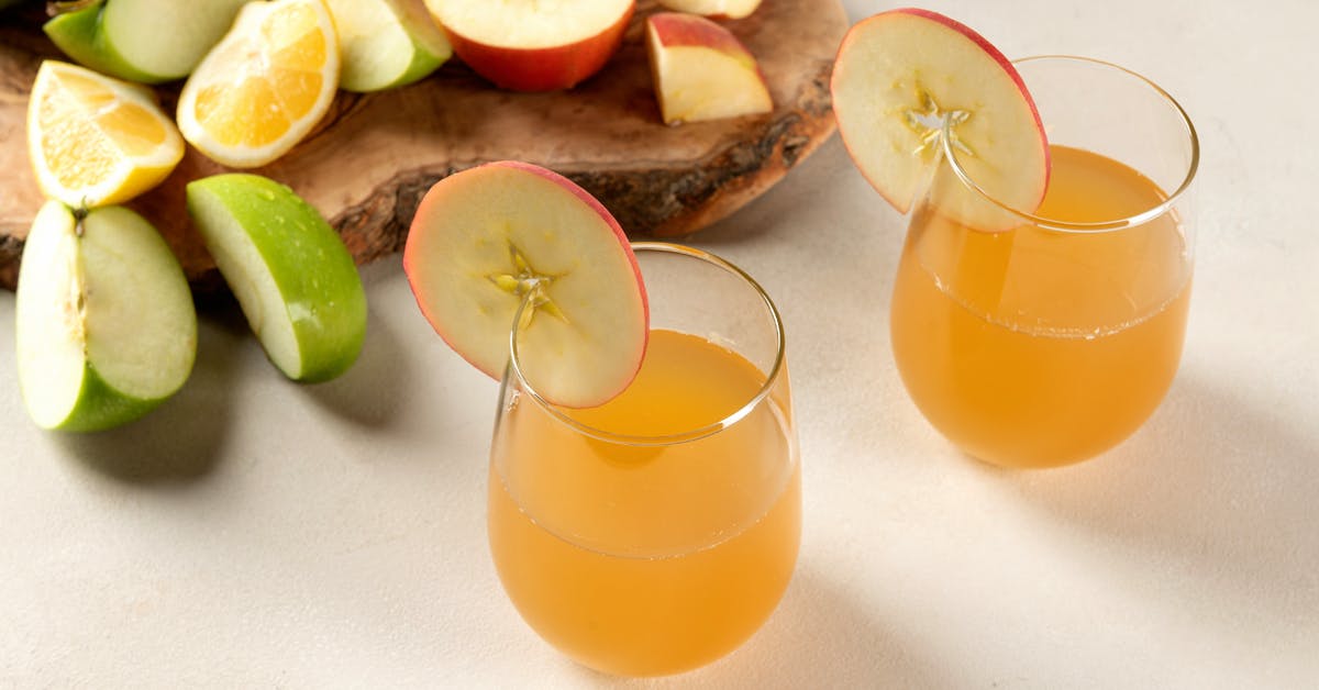 two glasses of homemade apple juice on a white table