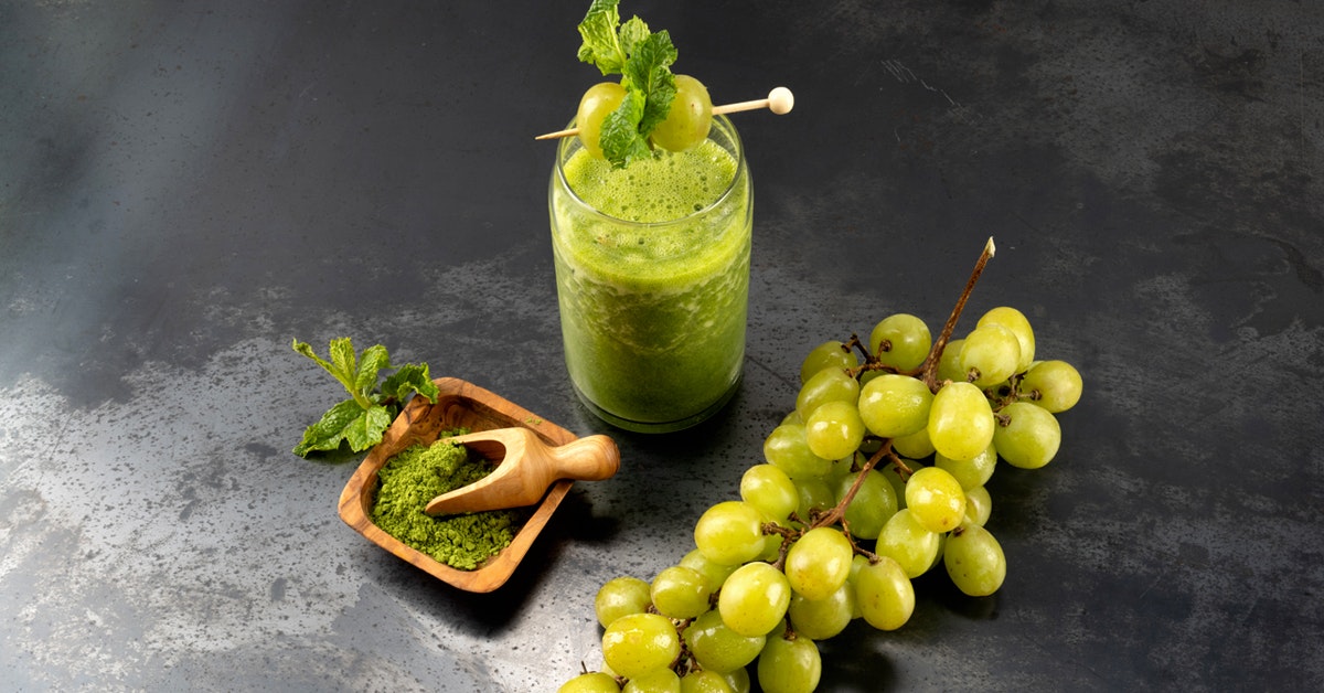 matcha smoothie with green tea matcha powder and grapes on a slate countertop 