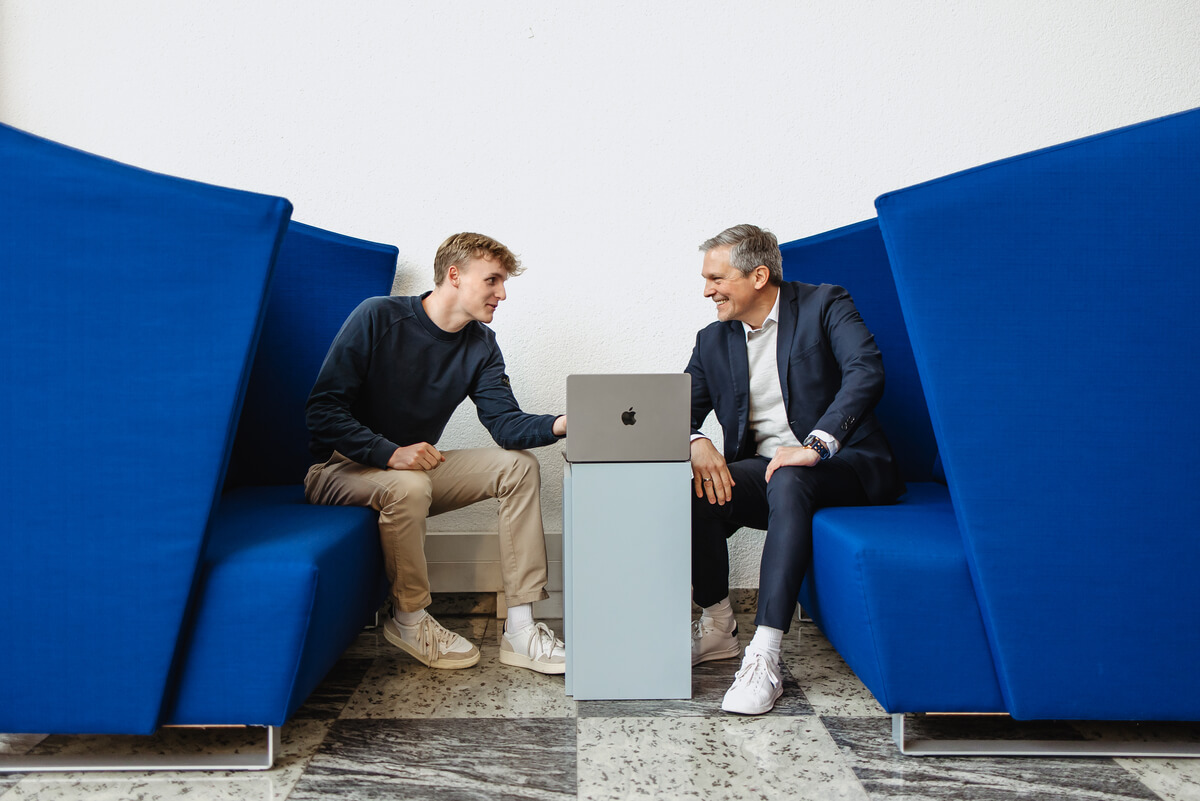 Zwei Männer beugen sich über MacBook und diskutieren
