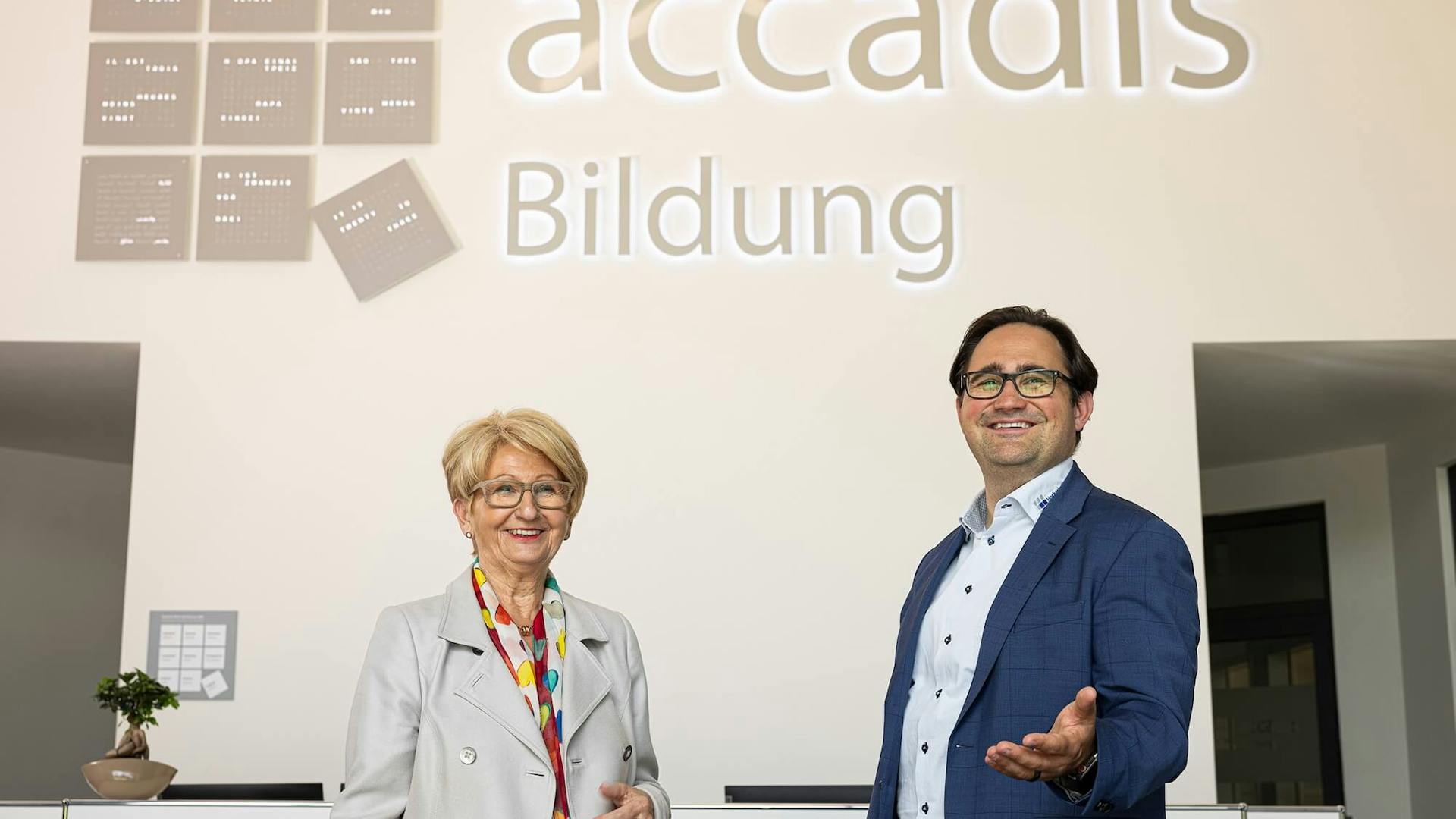 Accadis Mitarbeiter präsentieren sich vor dem accadis Bildung-Logo