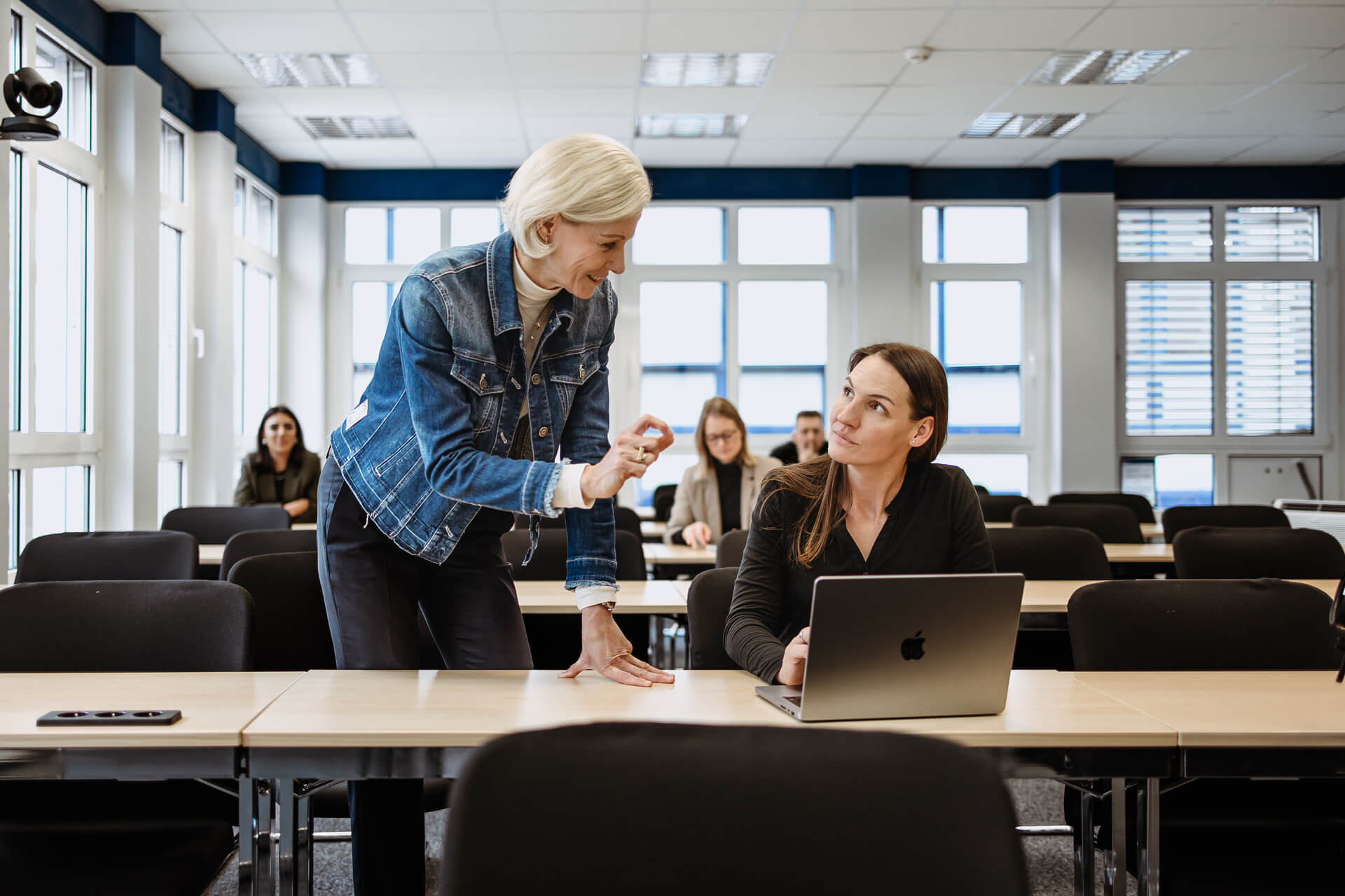Eine Professorin und eine Berufswechslerin unterhalten sich im Klassenraum.