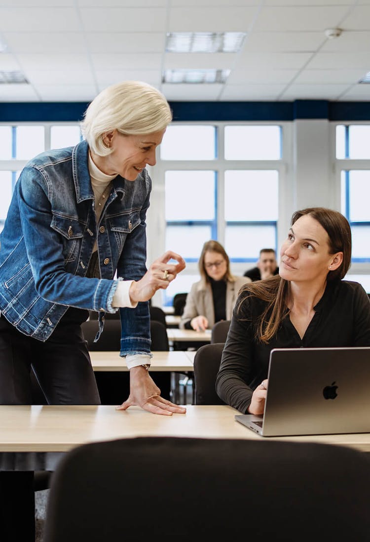 Eine Professorin und eine Berufswechslerin unterhalten sich im Klassenraum.