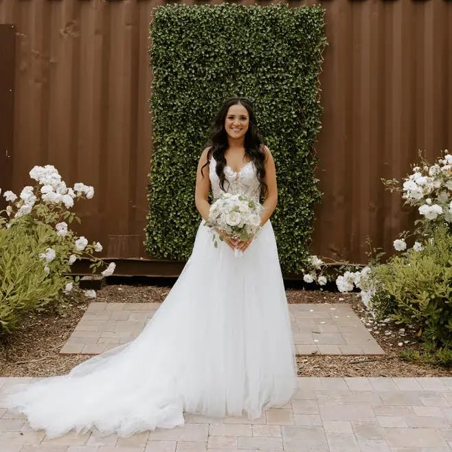 A bride smiling and facing the camera with her bouquet.