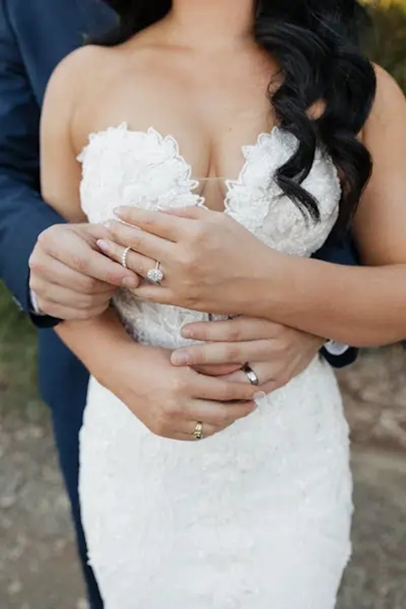 Bride embraced by groom from behind.