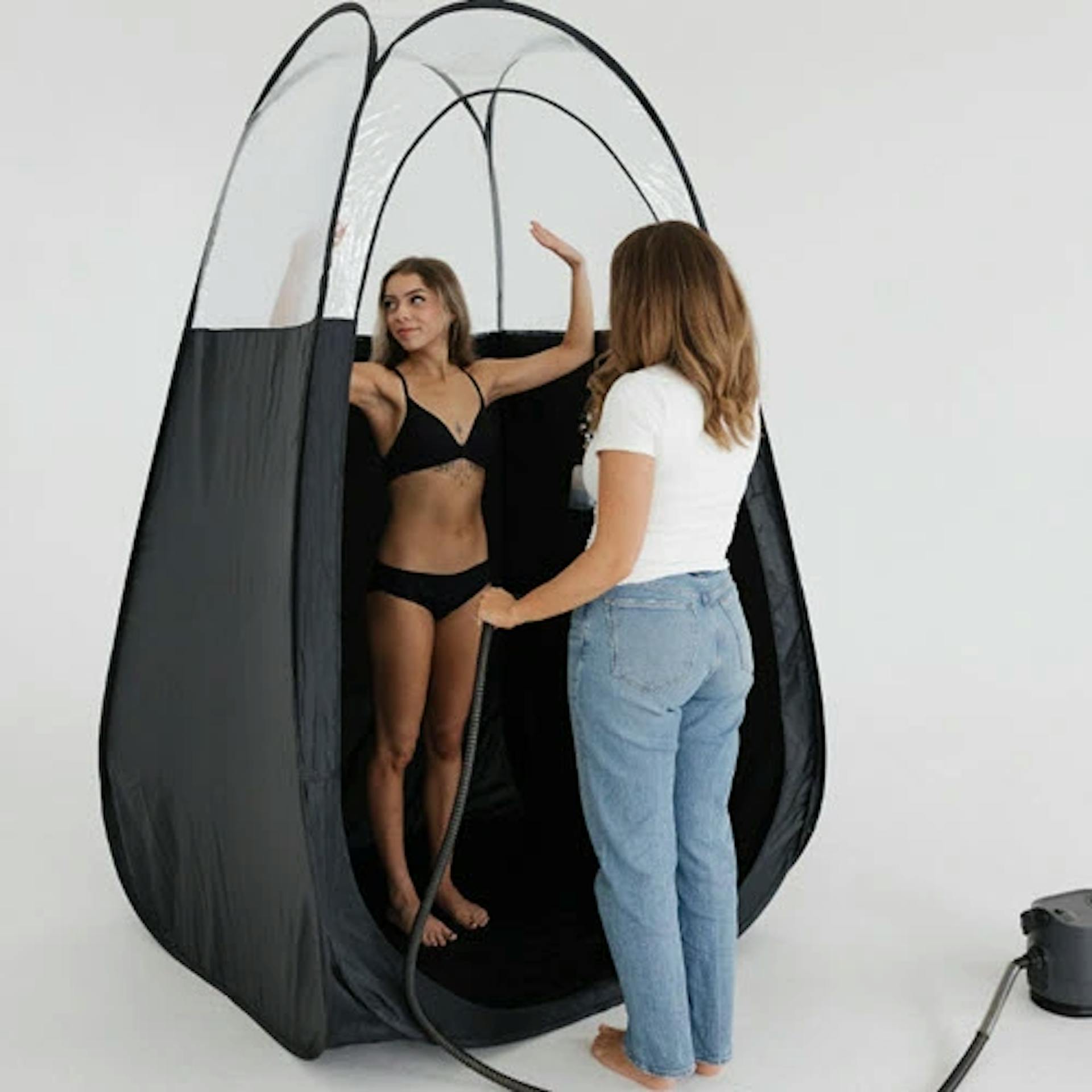 Grace training a student with a spray-tanning demonstration.