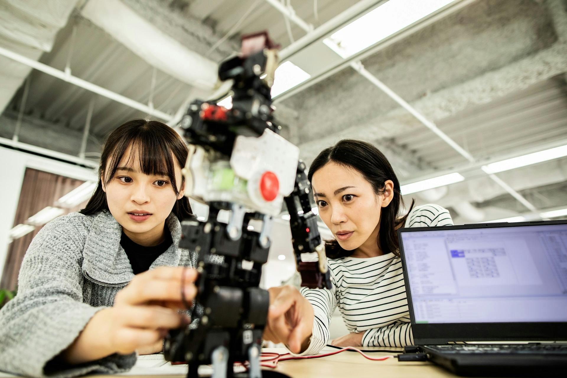 Two scientists study a robot prototype in a lab.