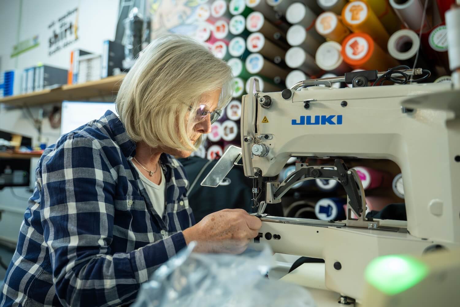 Mitarbeiterin von Grafik Idee veredelt Textilien an der Nähmaschine