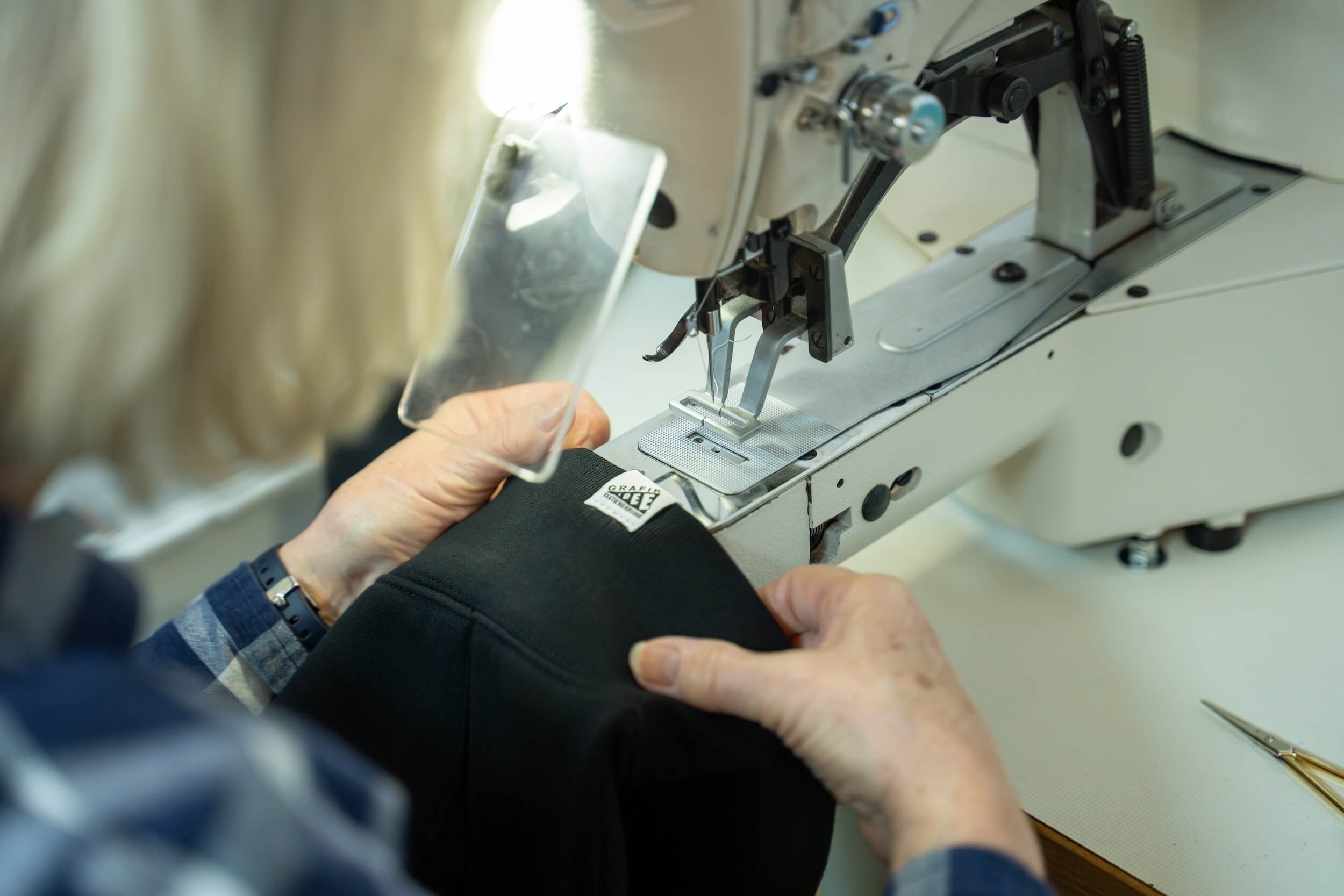 Woven-Label wird mit einer Nähmaschine an Tshirt genäht