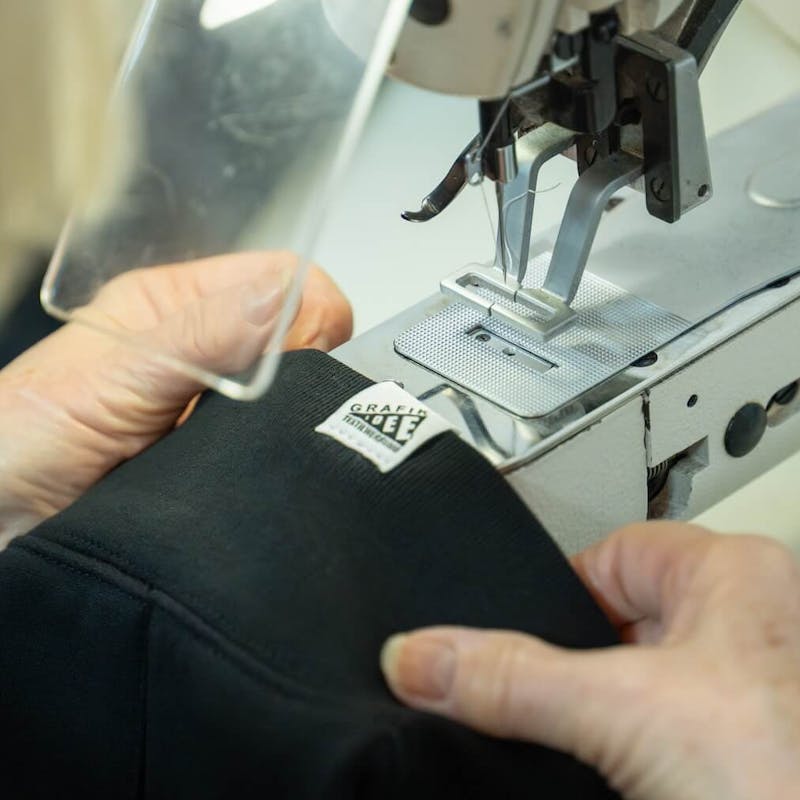 Woven-Label wird mit einer Nähmaschine an Tshirt genäht