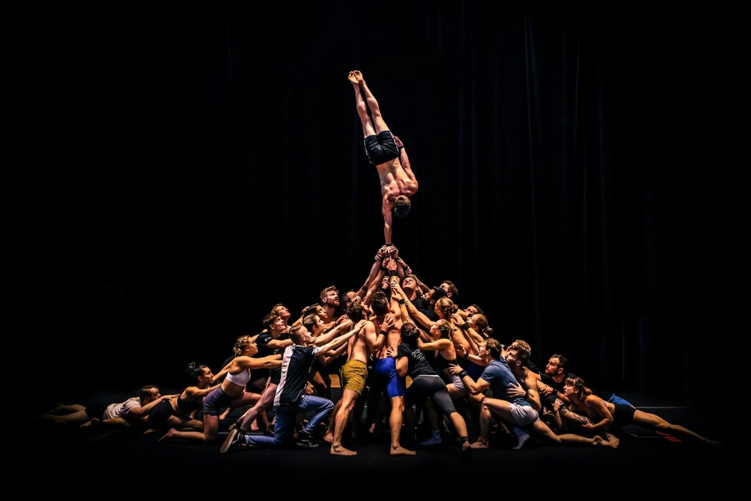 Man doing a handstand. Supported by a group of people.