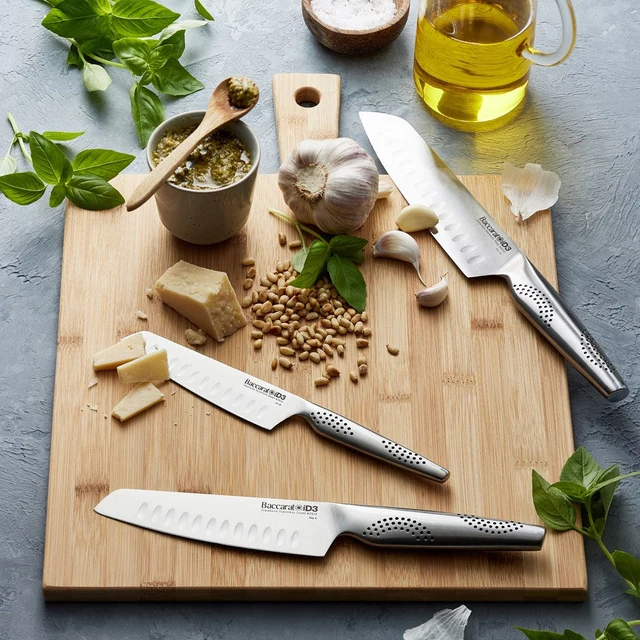 An overhead view of Baccarat iD3 Japanese Steel 3 Piece Santoku Knife Set on a wooden chopping board. 