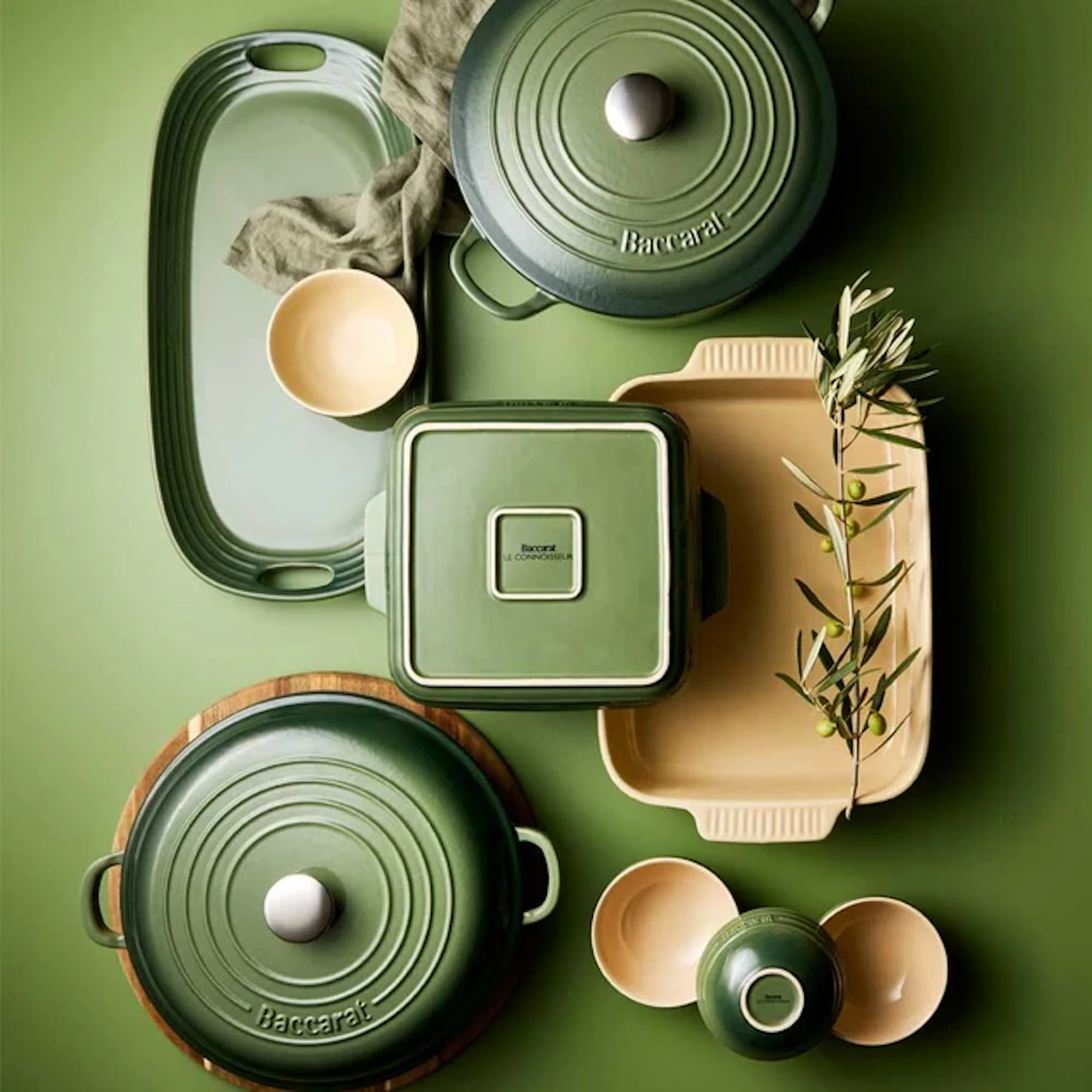 An overhead view of cookware sets and utensils is arranged on a green background.