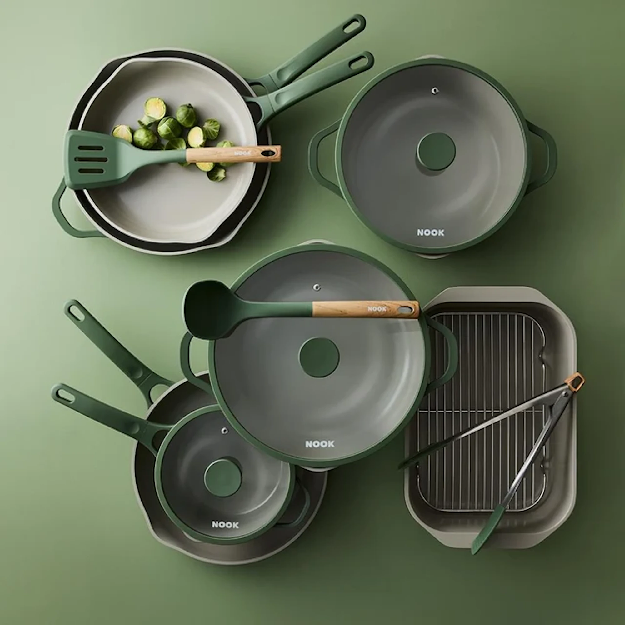 Sage cookware sets and utensils are arranged on a green background.