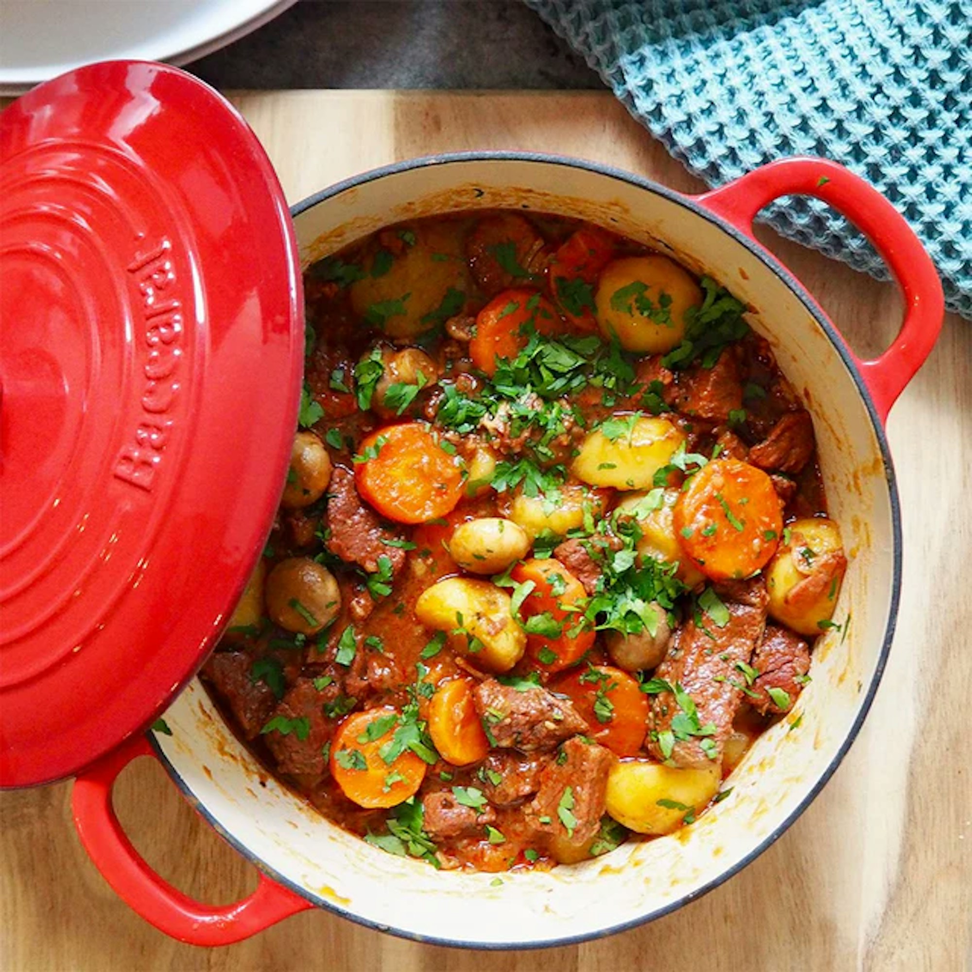 A red cast iron pot filled with a vegetable stew.