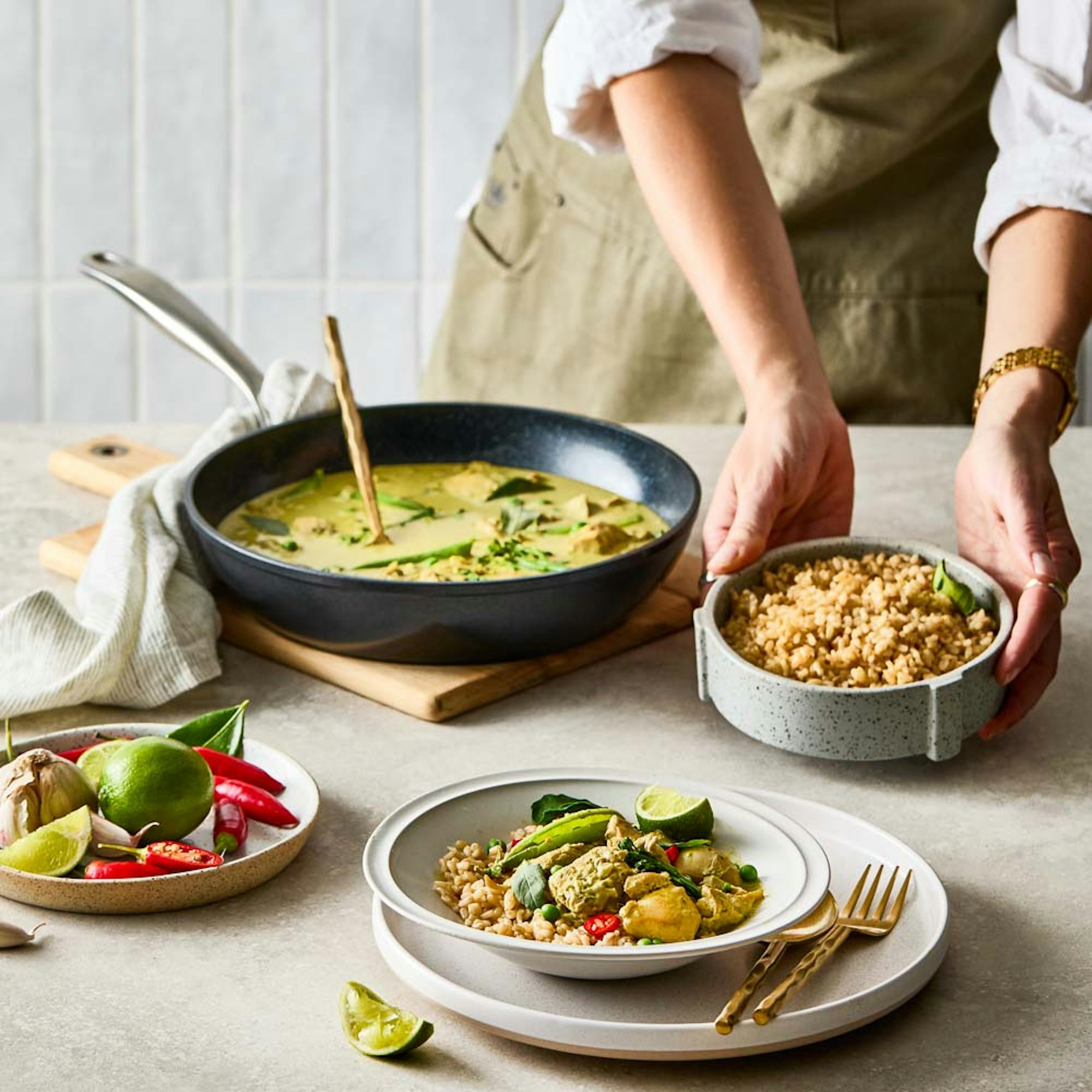 Woman serving thai green chicken curry with a side of rice. Baccarat GREEN STONE® 28cm frypan.