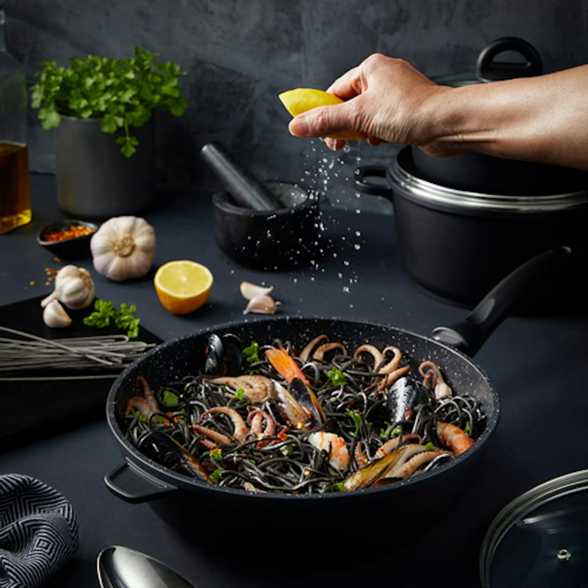 Lemon being squeezed into a wok containing a stir fry 