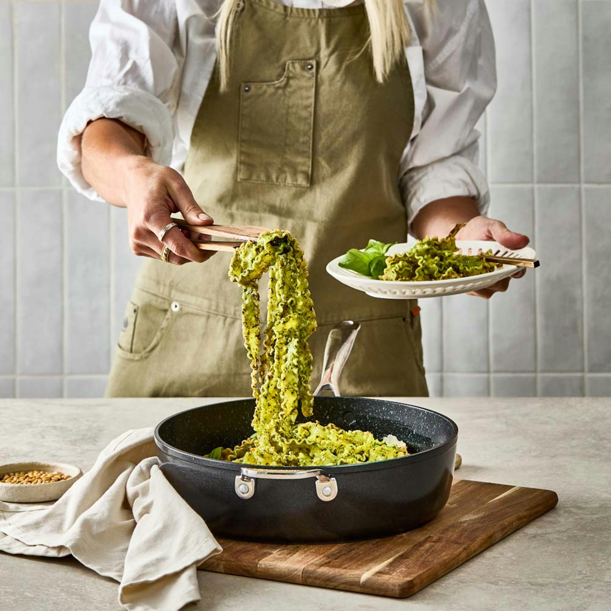 Woman serving pesto pasta from Baccarat GREEN STONE Chef pan.