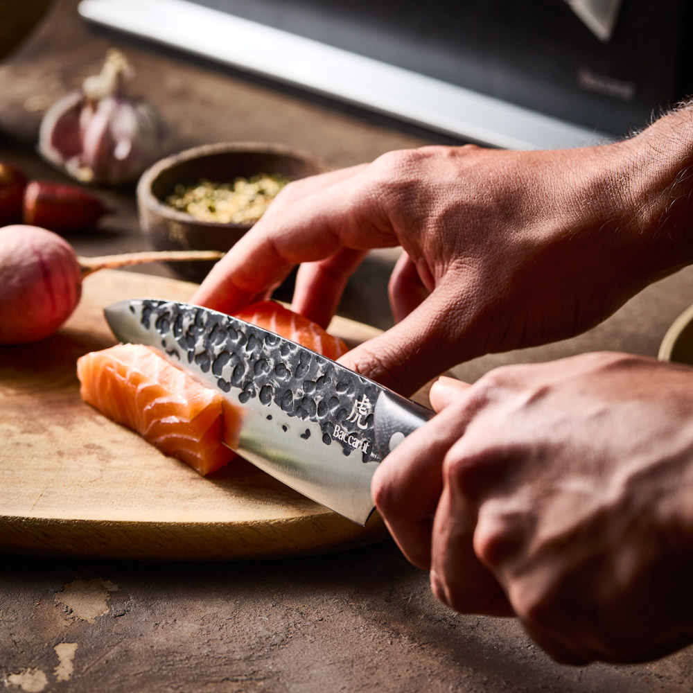 Kuroi Kiba santoku knife cutting salmon on a chopping board