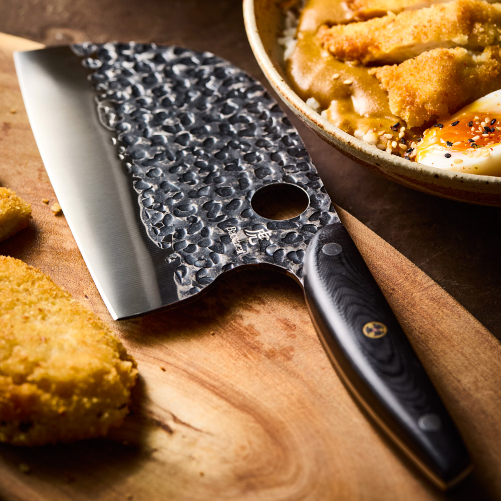 Kuroi Kiba moon knife laying flat on a chopping board