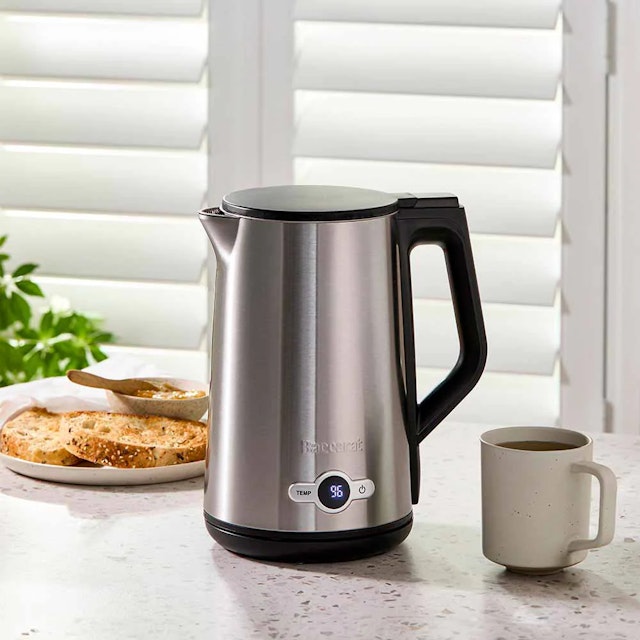 Silver kettle on a bench with a coffee cup