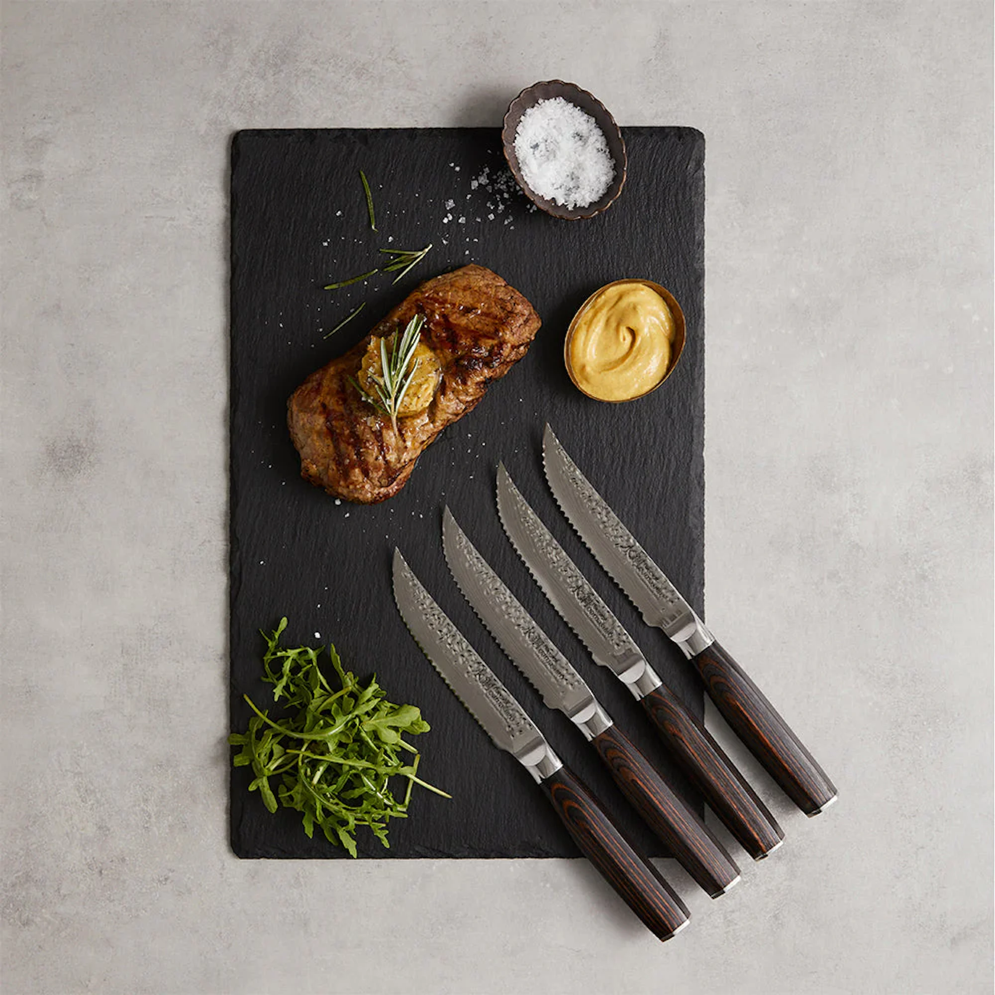 Damashiro EMPEROR steak knives on a cutting board with food