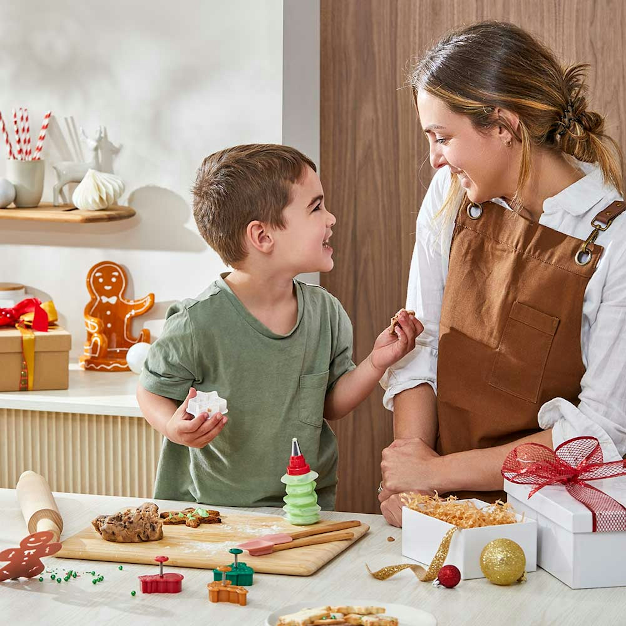 Mother and son looking at each other baking cookies in the kitchen.