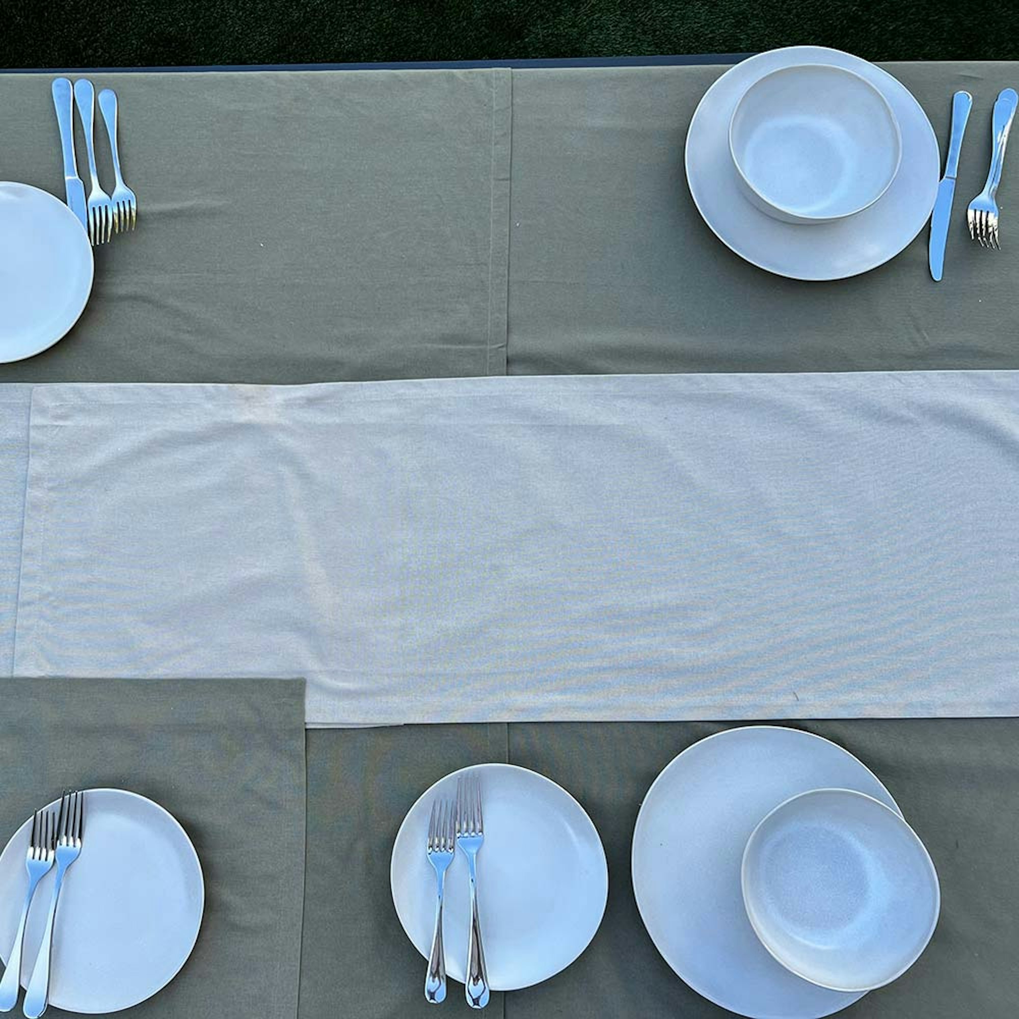 How to style a dining table for a dinner party. Step 4 setting the table. Overhead of table with table linen, dinner set, and cutlery.