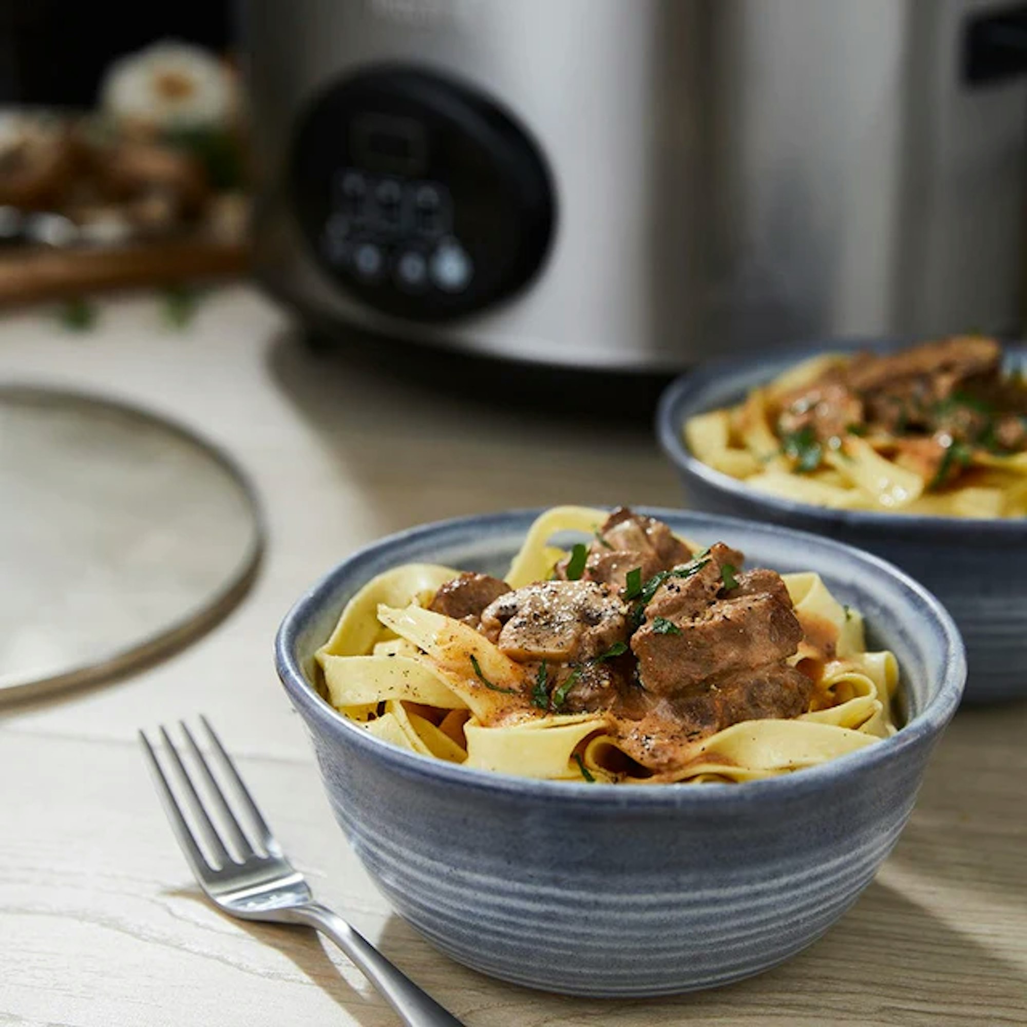 cooked meals from a slow cooker presented in a bowl on a kitchen benchtop with a fork