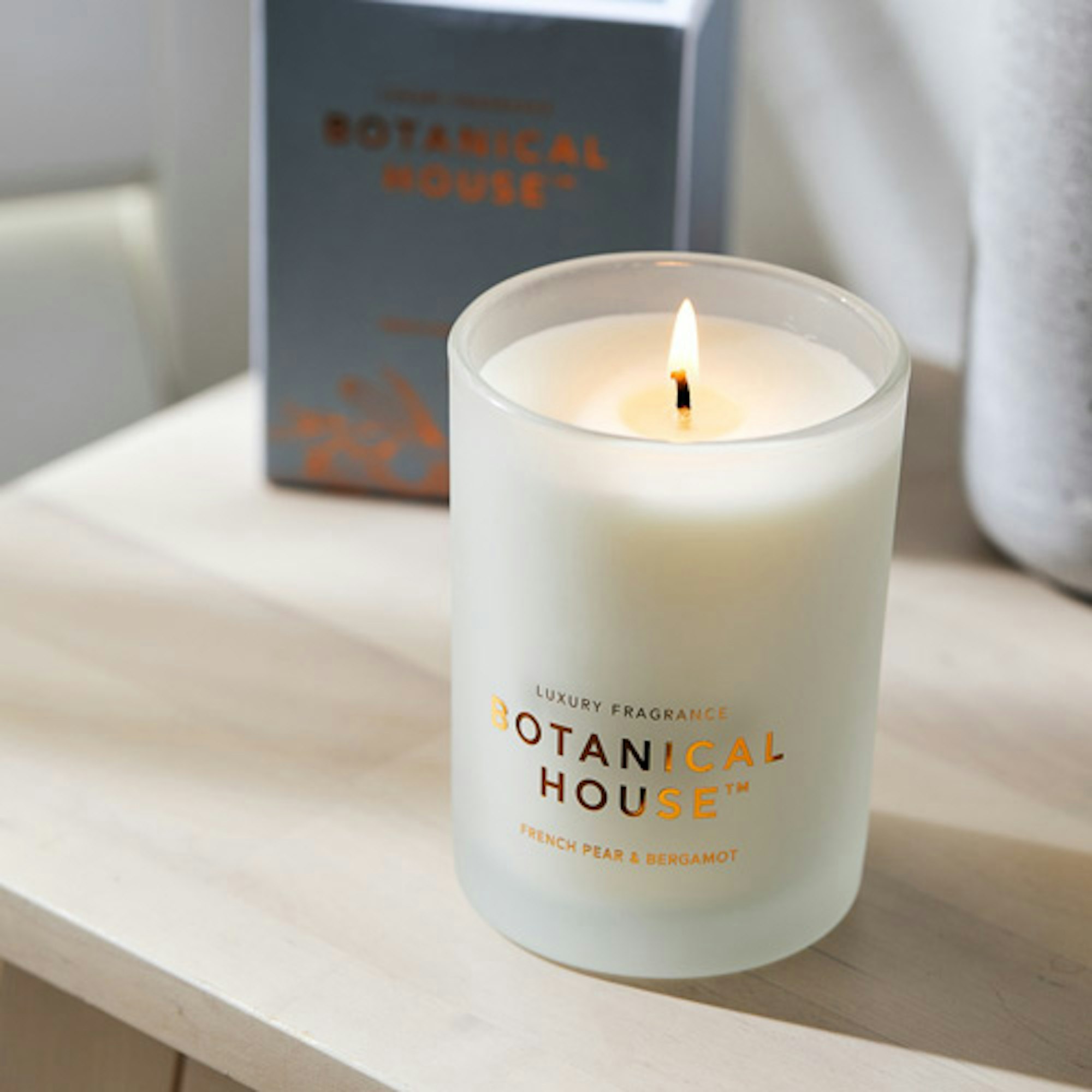 Botanical House scented candle. Lit candle with soft background.
