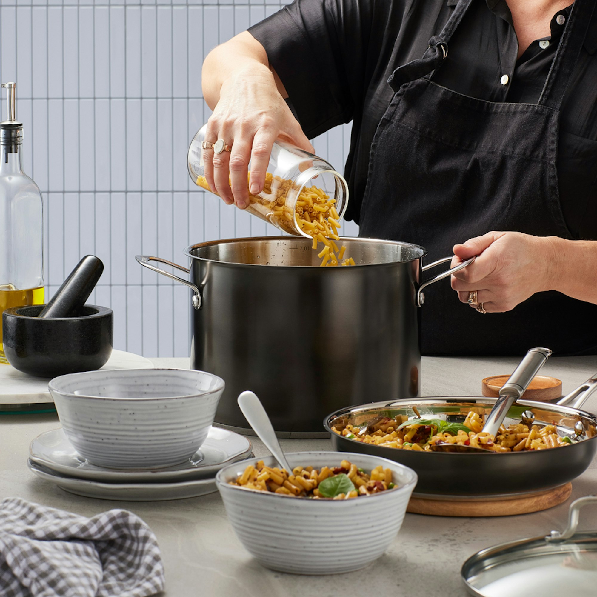 Cooking lifestyle photo woman pouring pasta into a black stock pot