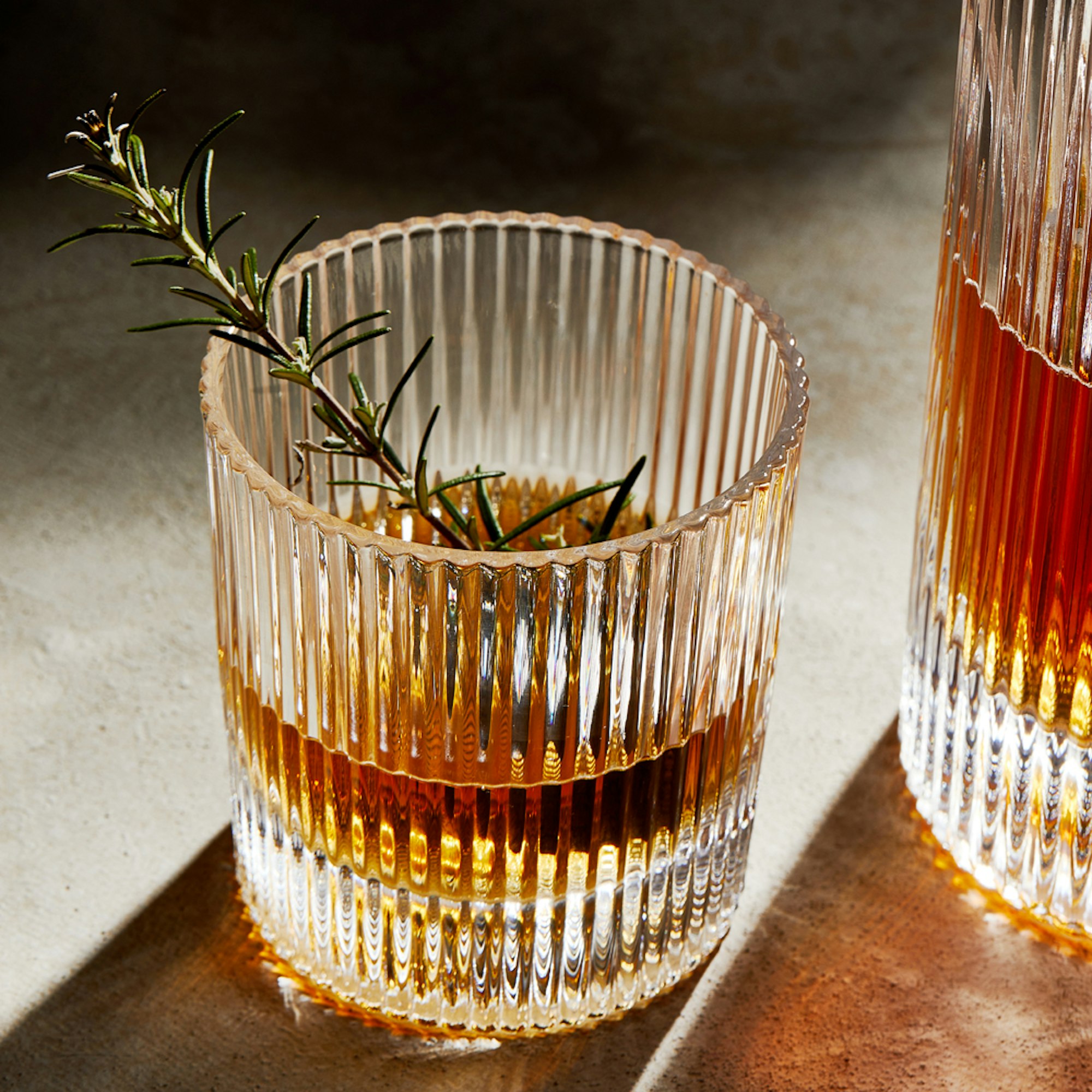 Old fashioned cocktail with whisky glasses and sprig of rosemary