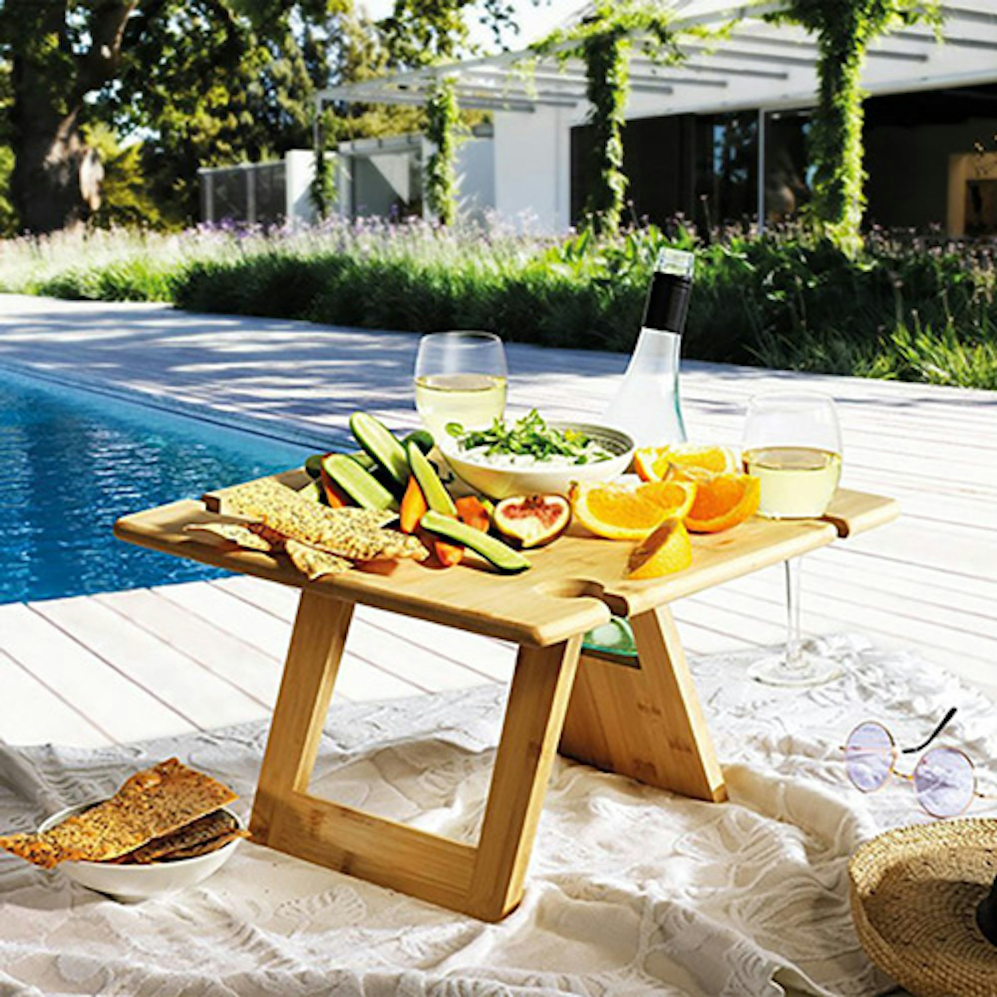 Picnic tray by poolside with wine and food