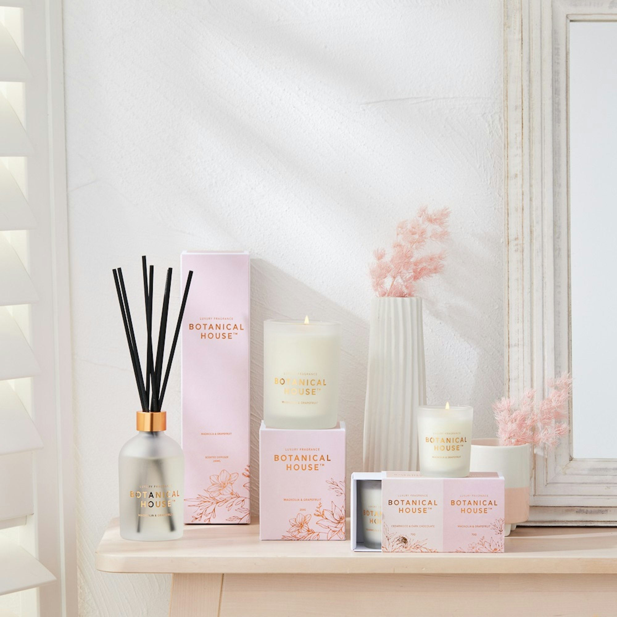 Botanical House Home Fragrance Collection. Scented candle and reed diffuser with pink packaging.