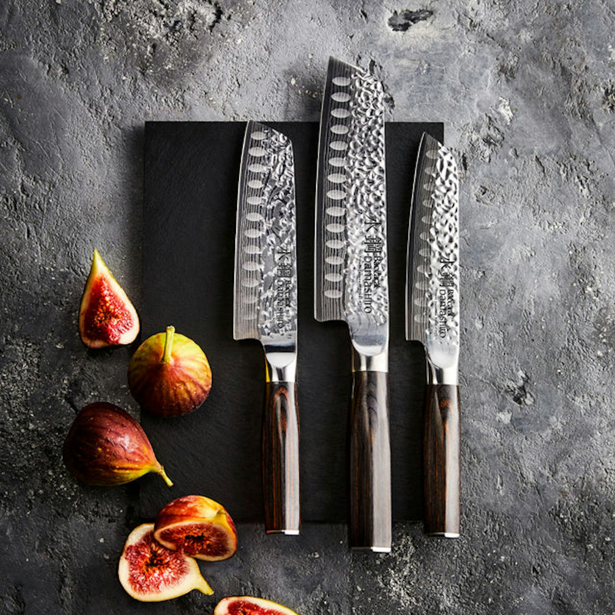 santoku knives in various sizes on a chopping board with figs