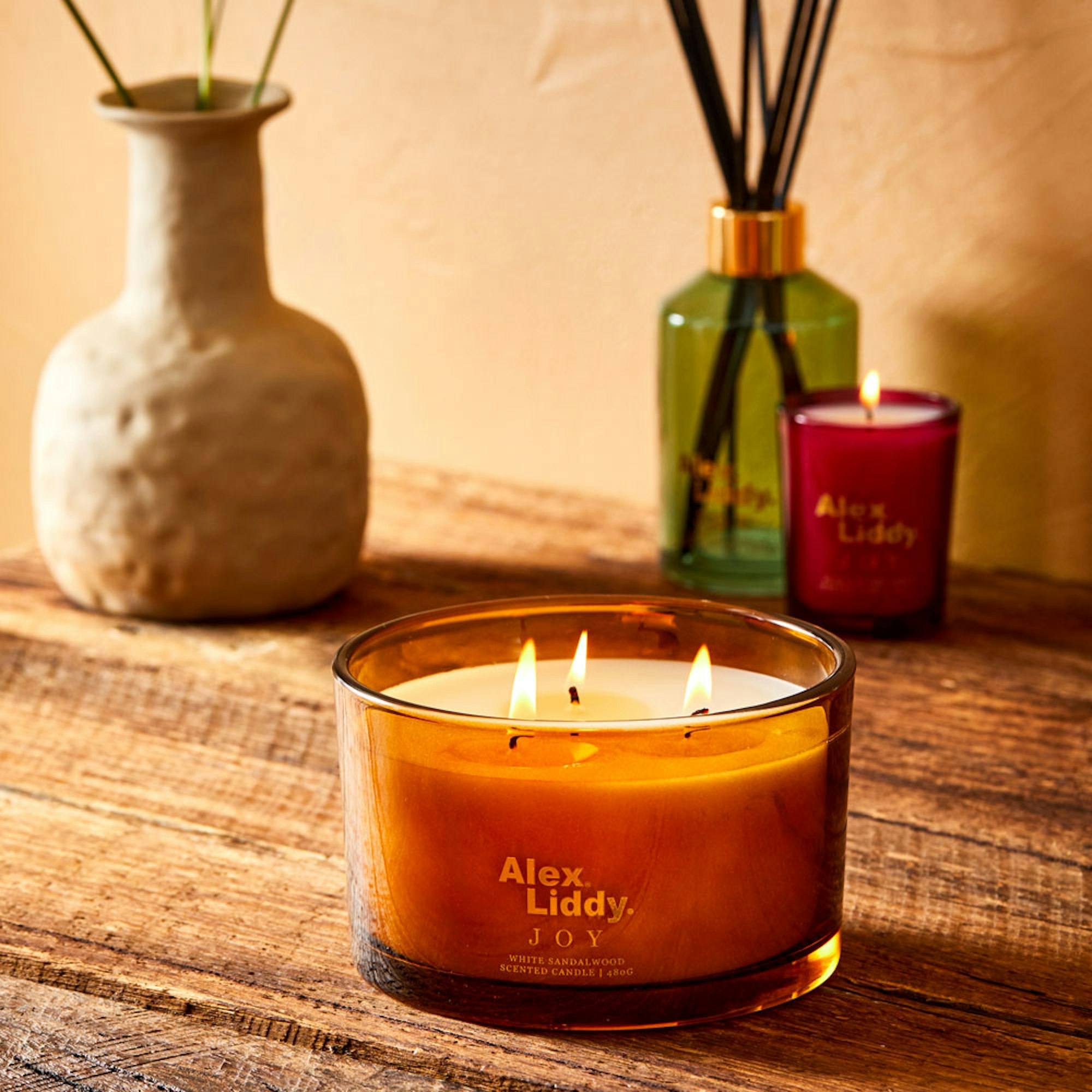 Your Ultimate Guide to Secret Santa Gift Ideas. Joy 3 wick candle lit with matching votive candle and diffuser.