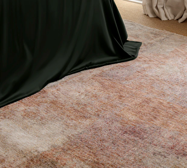 Close-up of Darren Palmer Sierra Dusk rug showcasing the distressed dusk-toned texture in soft rust, beige, and taupe hues beside dark green bedding and floor-length curtains