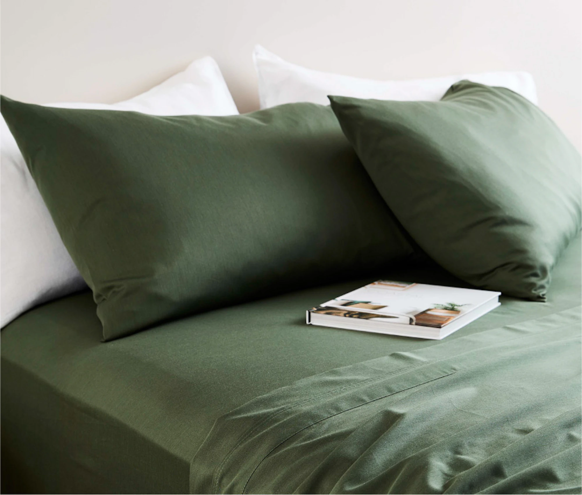 A beed sheet and matching color pillows on the bed