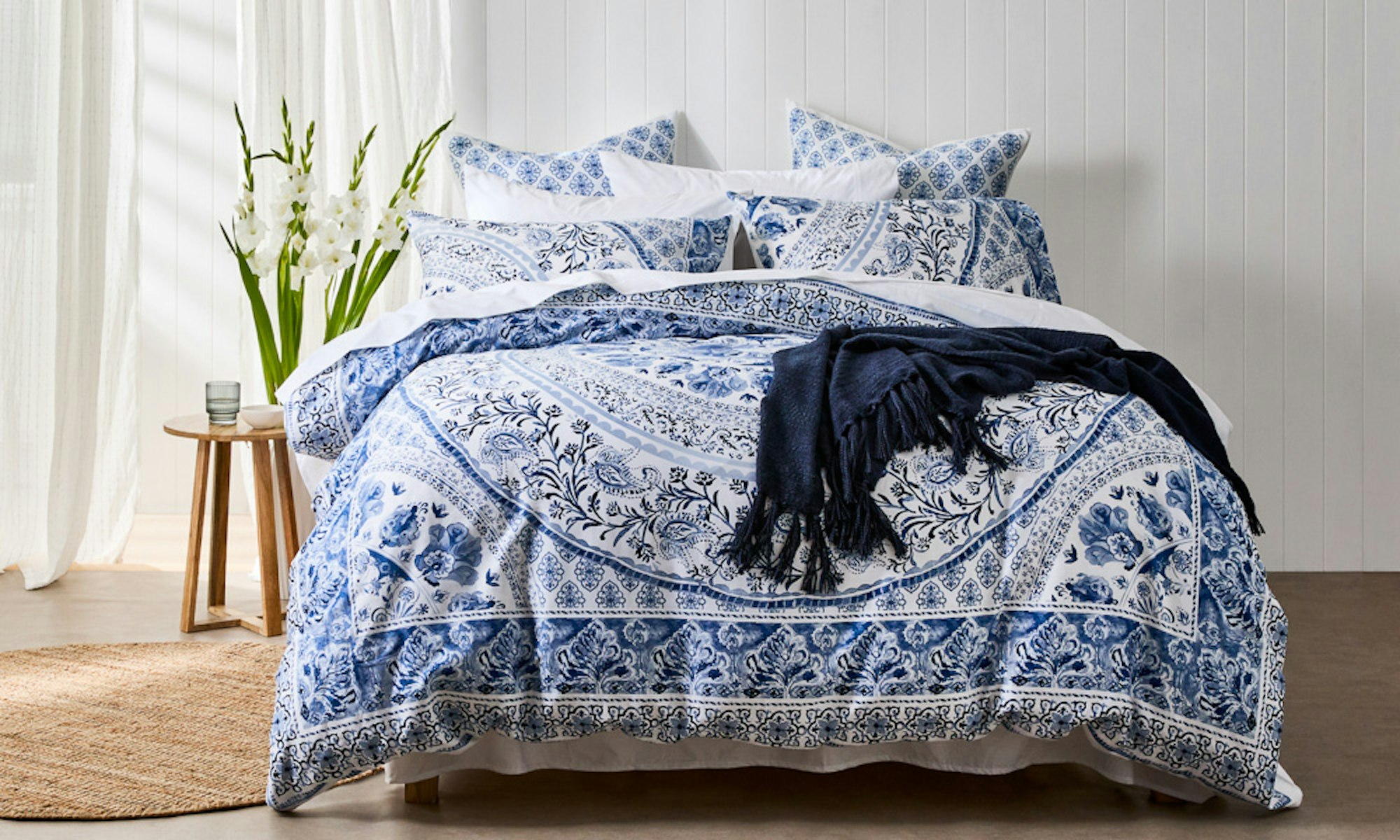 Home with Deborah Hutton SS23 coastal bedroom setting with blue and white medallion print quilt cover and navy throw