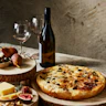 wine glass and bottle with pizza on a kitchen table