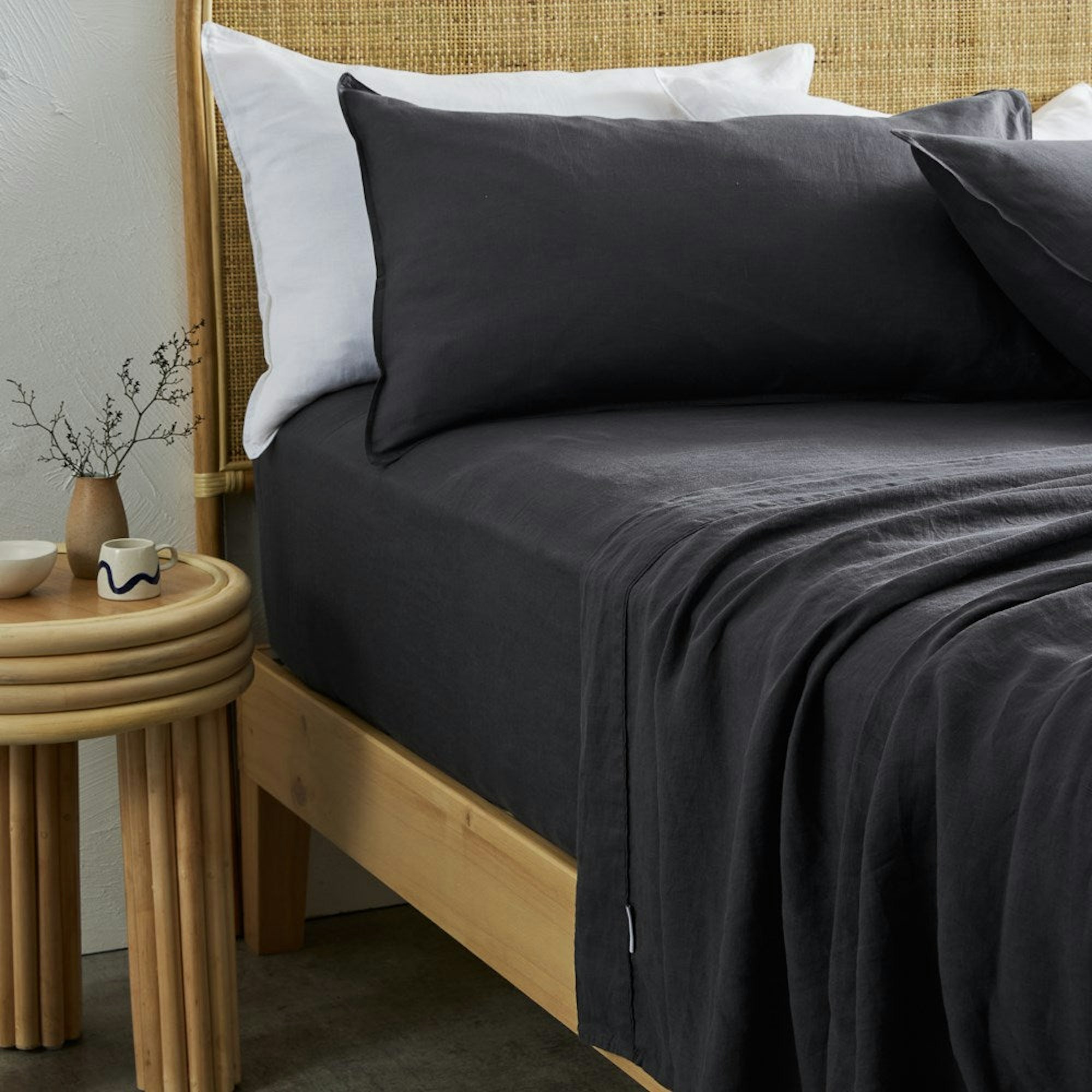 Complete bed setting with charcoal linen sheets and a side table