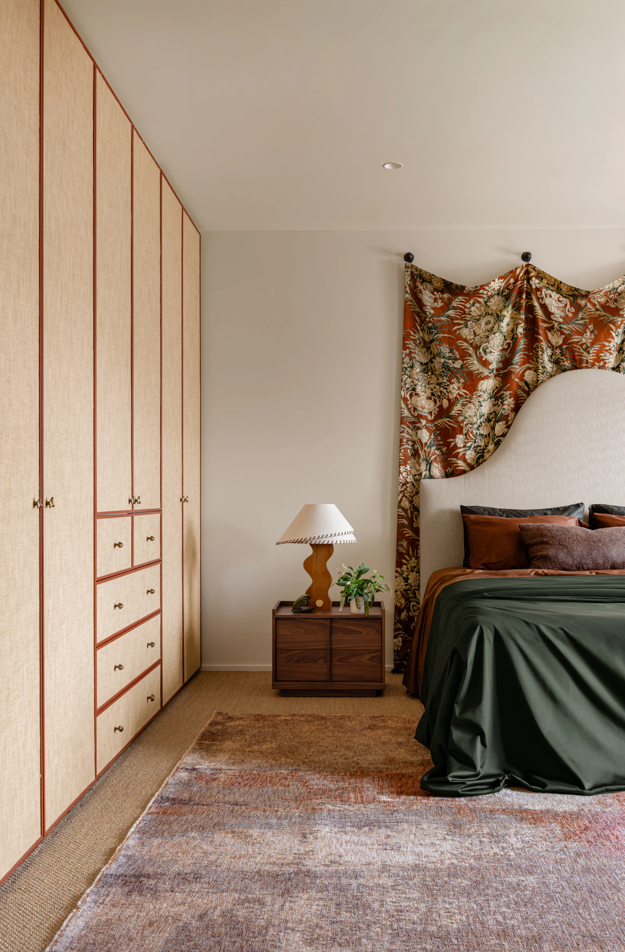 Darren Palmer Sierra Dusk rug styled in a contemporary bedroom with dark green bedding, floral drapery, and a distressed dusk-toned rug beneath the bed and bedside table