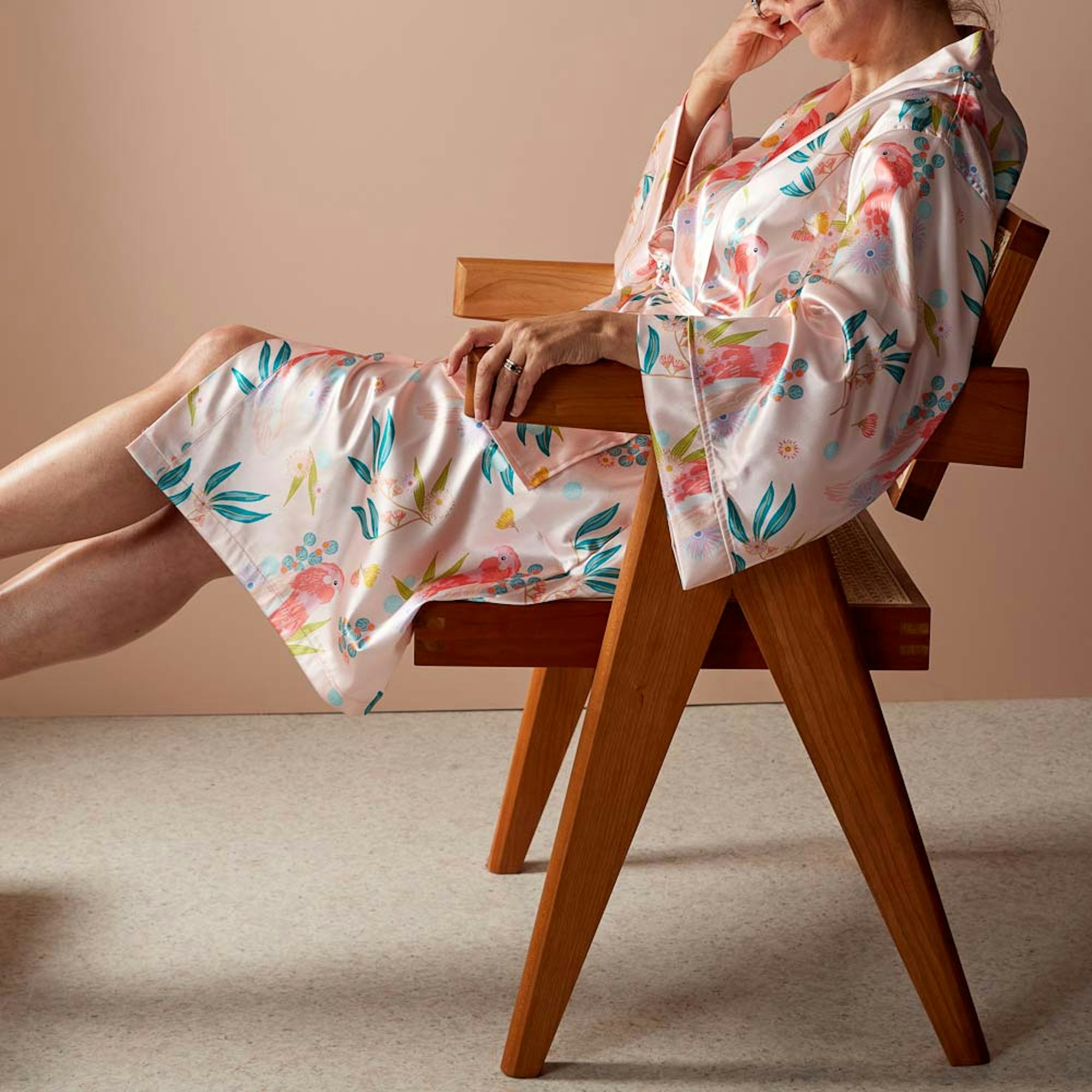 Woman lounging in a chair wearing a pink printed kimono.