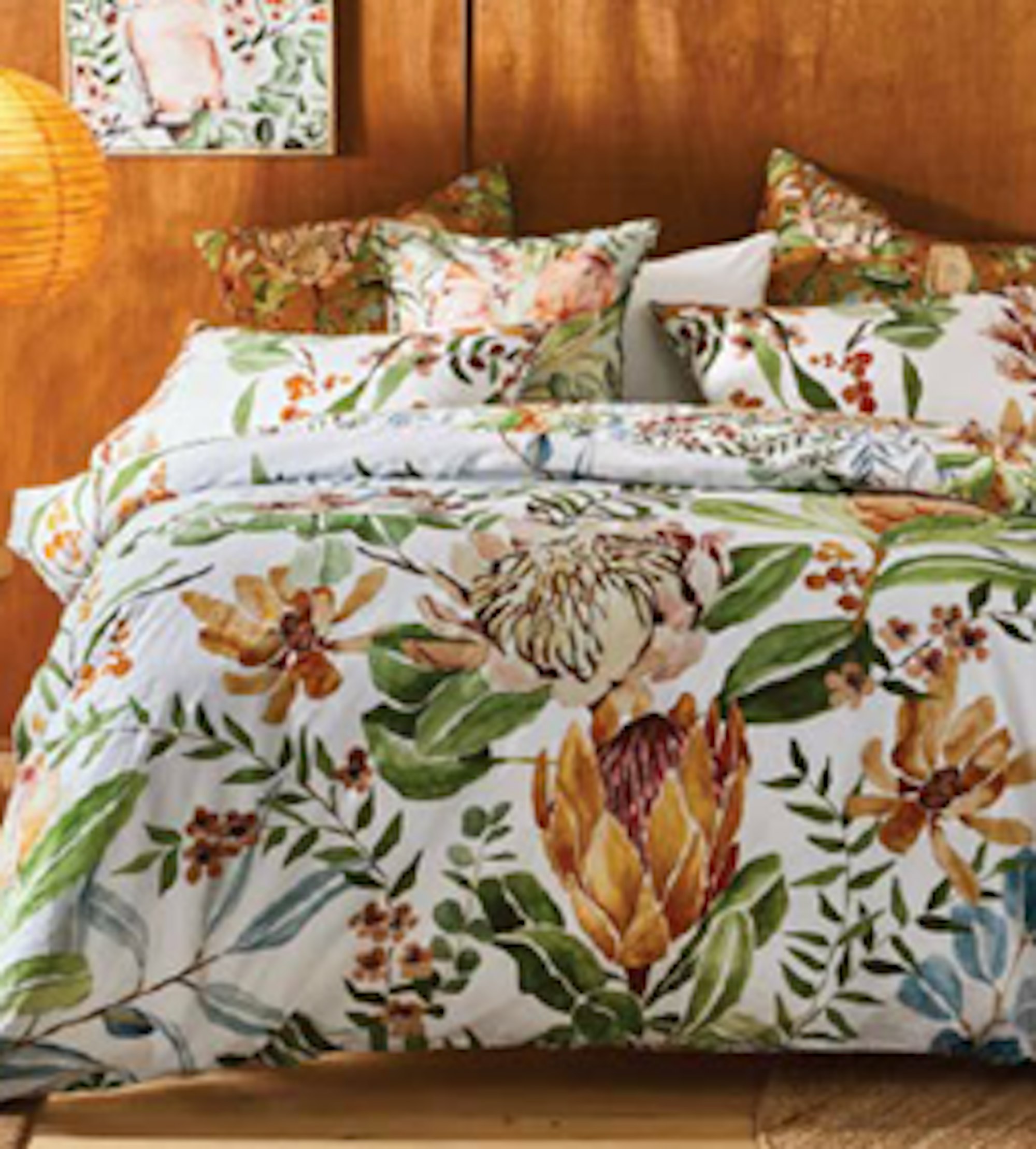 White quilt cover set with native Australian plant illustrations in front of a wooden wall