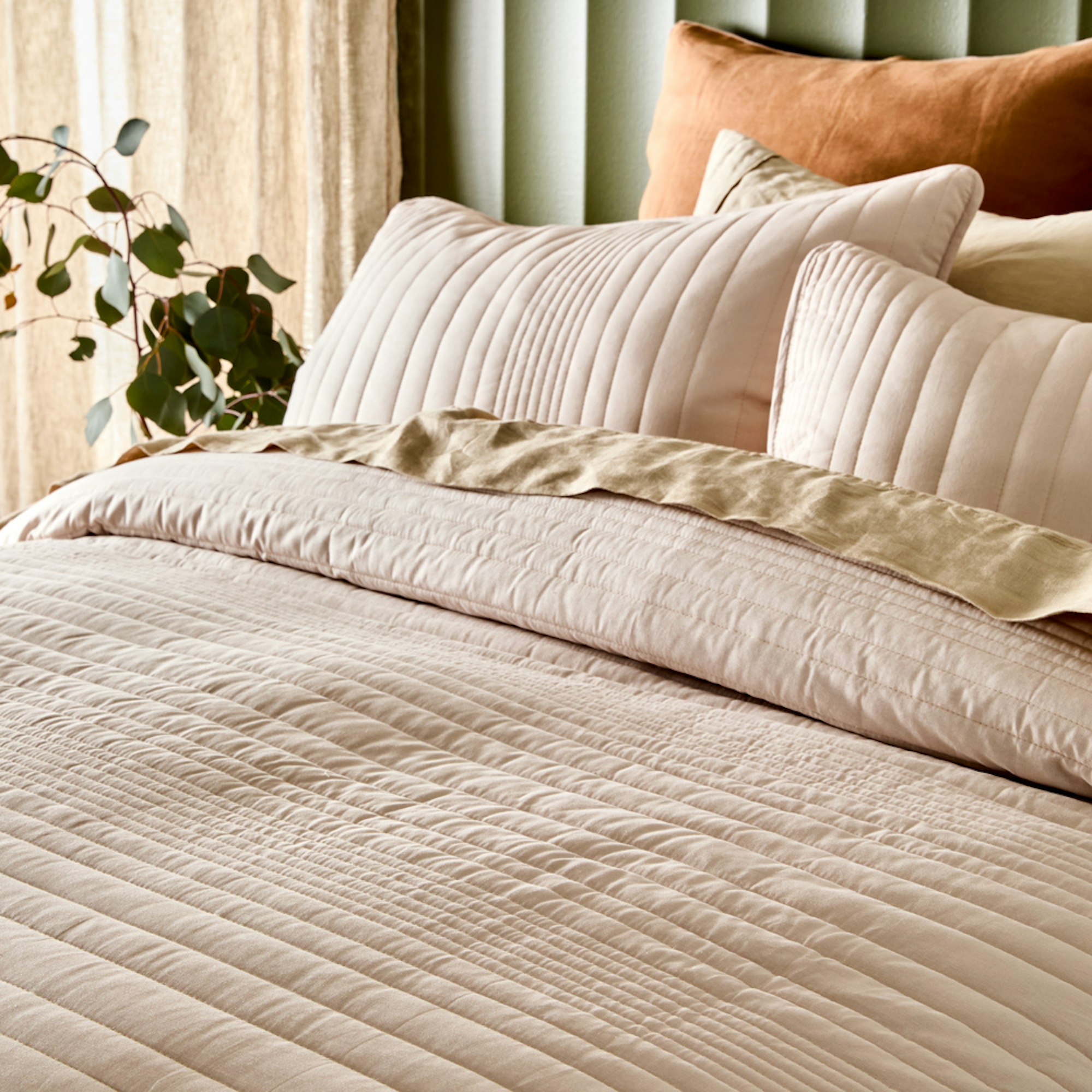 Cream quilt cover with a green wall - How to style your bed for better sleep blog
