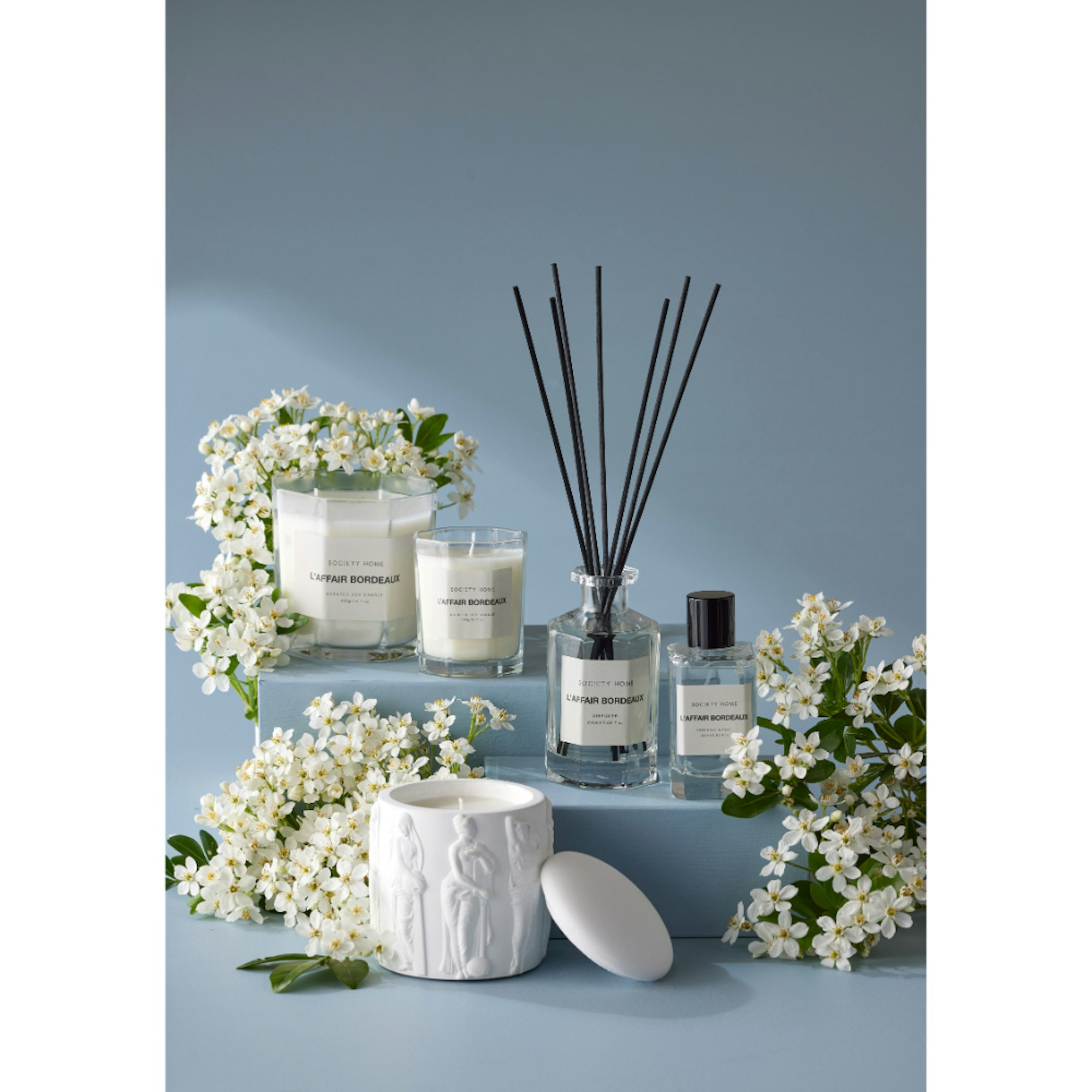 Candles and reed diffusers with blue background - How to style your bed for better sleep blog
