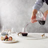 kitchen table with red wine being poured into a wine glass