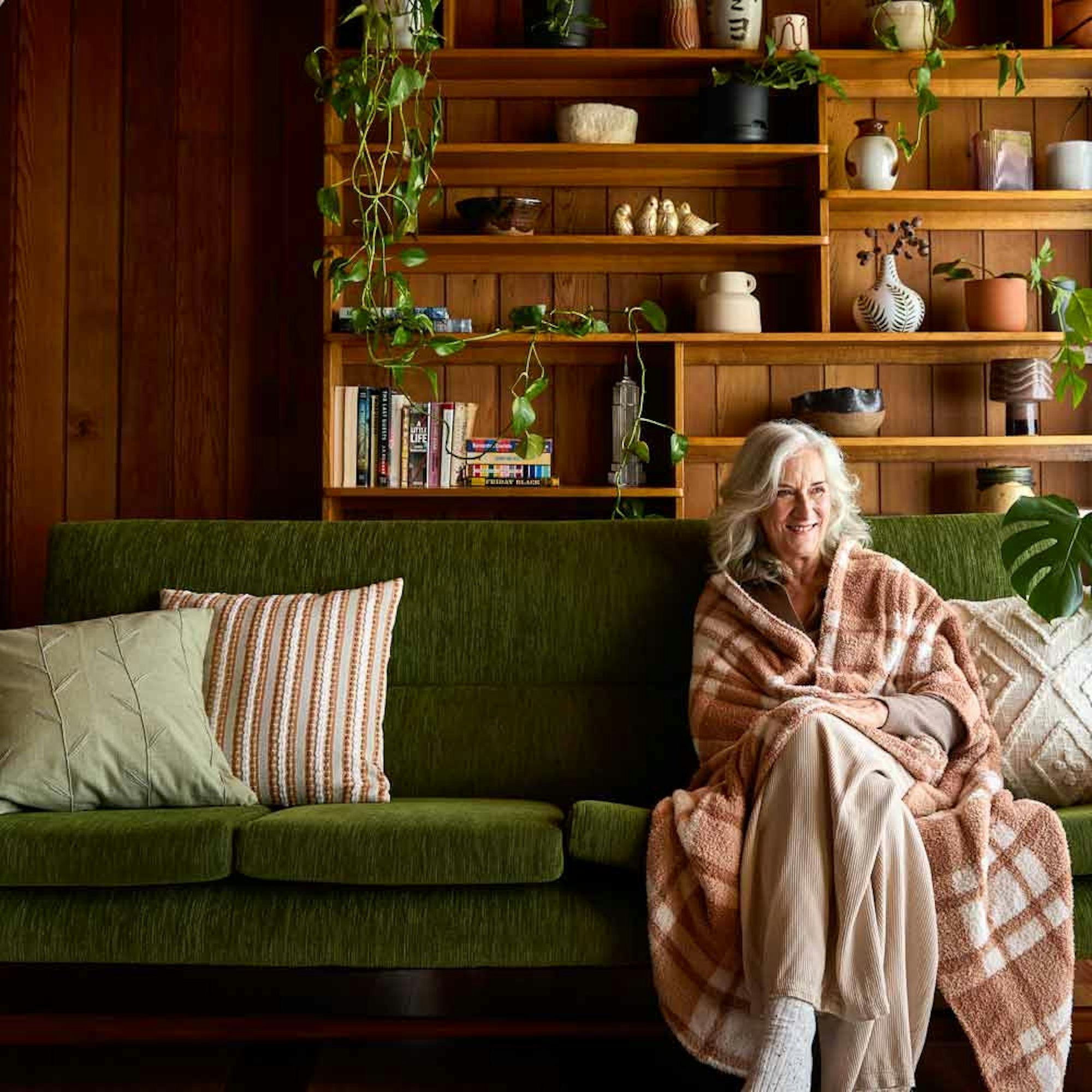 older woman sitting on the couch wrapped in a blanket - gift ideas for her