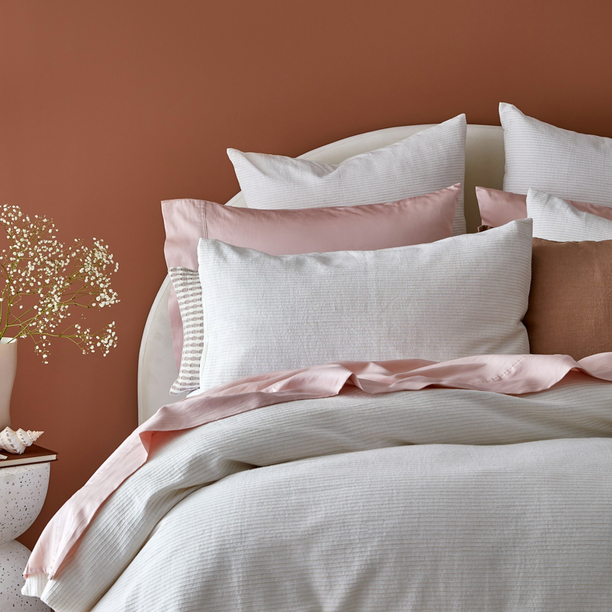 Home Beautiful Haven Quilt cover Set. while quilt cover set with pink sheets and warm rust background.
