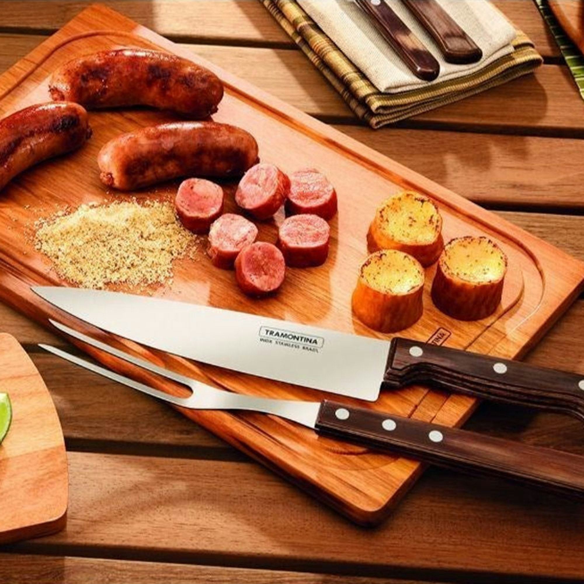 Guide to Secret Santa Gifts. Barbeque Accessories. BBQ carving set with wooden handles on a chopping board and sausages.