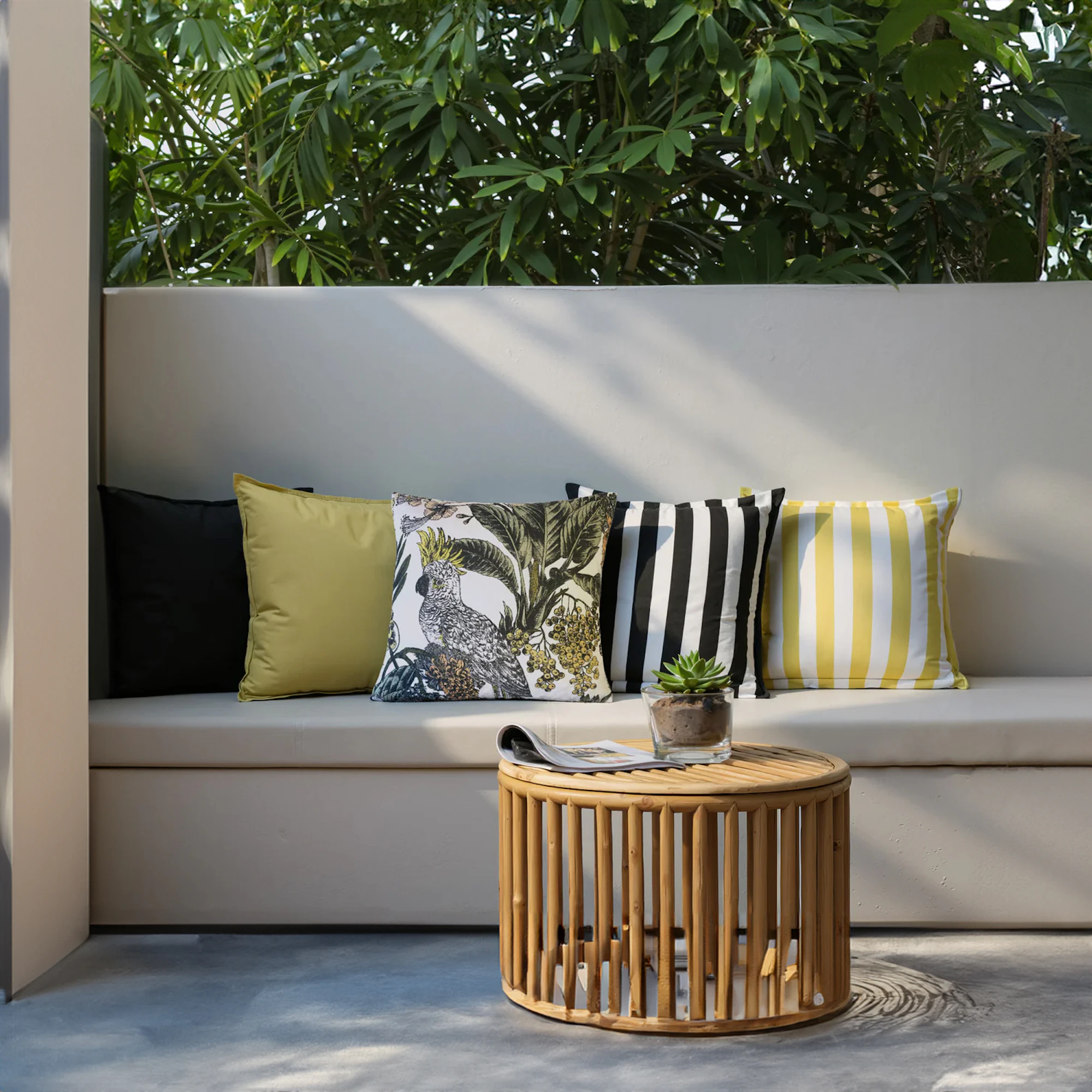 Zaab Cockatoo Outdoor Cushions styled on an outdoor bench with tropical bird print and striped pattern